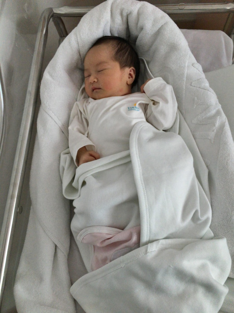 REVIEW COMBO ĐAU ĐẺ THƯỜNG & ĐẺ MỔ TẠI VINMEC TIMECITY

Hôm nay là hơn 4 tháng sau khi sinh bé rồi mình mới có thời gian ngồi viết lại review chi tiết cho chị em (vì nhiều ce hỏi quá mình ko trả lời hết và cặn kẽ được), cũng coi như kỉ niệm đi sinh bé Pi 
 Trước sinh: 
* Mình mua Gói sinh thường 36w trực tiếp của Vinmec Timecity, mua tại hội thảo được giảm 2tr, còn 35tr.
Mua gói 36w thì được khám từ w34, lần đầu mình khám đặt bác sĩ Dung, bác nữ, trẻ, nhẹ nhàng, siêu nhiệt tình, cho cả sđt để về alo khi có vấn đề bất thường vì mình trong nhóm nguy cơ tiểu đường thai kì và nhà thì ở xa Timecity. Những lần sau mình khám các bác khác tuỳ theo lịch vợ chồng mình rảnh, bác Thái nữ, bác Thái nam, bác Tuấn, ... Tóm lại thì bác nào cũng chuyên môn cao, nhiệt tình và nhẹ nhàng cả 
* Mình dự sinh ngày 15, ngày 13 thấy lo lo nên đi khám, 2 vợ chồng vác cả va li đi vì nghĩ sẽ đẻ thôi, khám xong bác sĩ bảo chưa đẻ đâu, lại về :))). Ngày 16, đau bụng nhẹ và ra ít huyết nâu, xách vali đi đẻ tiếp, bác sĩ bảo không sao, về đi. 1h sáng ngày 17, đau bụng theo cơn, đau từ 9h tối ngày 16 rồi, 2 vợ chồng lại xách vali đi đẻ, đến nơi gần 2h. Xe đến nơi, 2 y tá ra đón, ngồi xe đẩy đẩy vô phòng chờ sinh cũng là phòng sinh luôn. Hành trình đi đẻ thực sự bắt đầu 
- Đau dữ dội theo cơn, có y tá, hộ lý vào, sau đó có bác sĩ vào, đúng ca bác Dung nên bác nhận ra mình ngay. Bắt đầu nằm đo monitor, sau đó khám trong. Nằm gần tiếng, y tá hay hộ lý gì đó vào kiểm tra liên tục mà bảo không có cơn co, không mở phân nào cả. Mình thì vẫn đau, bà hộ lý take care trực tiếp mình thật sự quá quắt: “Đau thế bình thường, chưa mở đâu, cũng không có cơn co, có người đau thế này cả tuần mới đi đẻ, chắc em nằm tí nữa rồi về thôi!” Mình vẫn bảo em đau lắm, bà í đi ra, mình bảo chồng mình ra báo bác sĩ Dung và bên quản lý để người khác care trường hợp của mình. Sau 3 lần chồng mình ra gọi thì bác Dung vào (vì đêm đó ít bác trực quá nên mn khá bận), bác khám cẩn thận cho mình rồi bảo mở 1 phân rồi, tiến hành các công tác chuyển dạ thôi, em yên tâm nhé! Thấy yên tâm hẳn huhu. Thật sự đến giờ nhắc đến Vin và chuyện đi đẻ thì chỉ không hài lòng bà hộ lý đó thôi :))). 
- Sau đó thì có người vào sắp xếp đồ để mình chuẩn bị sinh. Y tá đặt ống thụt cho, được một lúc thì đau bụng và đi vệ sinh, thốn đến tận óc, vật vã luôn. Rồi cả đi làm vệ sinh cá nhân, tắm rửa. Và sau đó, đau, rất đau, chắc do mình chịu đau kém, mình bảo bác sĩ tiêm giảm đau suốt nhưng các bác động viên nên tiêm sau mở 3p sẽ tốt cho cuộc chuyển dạ hơn. Vì ca của mình kêu đau thảm thiết quá nên tận 3 bác luân phiên vào care, nhưng vẫn mở rất chậm. Hành trình mở từ 1 phân đến 3 phân của mình mất khoảng 10 tiếng tính từ 2h đêm hôm trước, đau dữ dội khi cơn co đến, lại còn khám trong liên tục, hic. Hôm sau là bác Vũ Duy Thái tiếp nhận ca của mình, bác Thái nam cũng là bác sĩ mình khám tuần cuối cùng trước khi đi sinh, may là bác vẫn nhớ mặt, bác động viên và siêu nhẹ nhàng. Tầm 12h trưa hôm sau, mở đc 3p nên mình được gây tê màng cứng, do bác Vũ Anh (nếu mình nhớ không nhầm) chọc đến lần thứ 2 mới gây tê xong, lúc làm thì hơi đau và sợ nhưng làm xong tầm 30’ thì cuộc đời lên tiên luôn. Hết đau, mình được ngủ lấy sức, bác và một phụ tá làm giảm đau dặn, nếu thấy đau, thường là khi mở đến 7-8p là đau nhất thì bấm cho thuốc xuống. Chị phụ tá bảo, cứ yên tâm bấm để thuốc xuống, không lo hết thuốc vì bọn chị tiếp thuốc liên tục nhé, không phải chịu đau. Cứ hơi đau là mình lại bấm, và lại hết đau ngay khi cơn co đến. Đúng là giảm đau thần thánh luôn, từ đấy hết đau các bác ạ :))). Sau đó, mở phân vẫn rất chậm, vẫn 3p mà gần 12 tiếng trôi qua rồi, bác Thái truyền kích đẻ cho mình. Đến tầm 3h chiều, mình mở được 8p, thấy đau nhiều hơn chút xíu. Đến 5h, vẫn 8p, bác Thái và bác Anh Thơ vào hỏi thăm, bác Thơ khám trong cho, cùng lúc í bắt đầu có dấu hiệu tim thai bị suy khi cơn co đến. Lúc đấy mình lo phát khóc luôn, chỉ thầm mong con nhanh chào đời bình an thôi. Bác Thơ bảo chuyển dạ lâu quá, xong bàn gì đó với bác Thái, bác Thơ bảo bấm ối nếu trong thì đợi mở đủ 10p. Một lúc sau, cả ekip vào tiếp, mình thì vẫn đau và vẫn 8p, bác Thái và bác Thơ hướng dẫn mình dặn, nhưng không được. Khám trong đầu em bé vẫn cao, không có dấu hiệu xuống thấp. Tim thai suy dần. Hai bác quay ra họp bàn tầm 1’, vào bảo: 2 vợ chồng chuẩn bị tinh thần mổ cấp cứu ngay nhé! Người nhà ra kí giấy mổ. Mình bật khóc nức nở luôn, vì lo cho con, vì không thể sinh thường, vì tiếc công chịu đau suốt gần 18 tiếng. Cứ khóc là tim thai lại suy, mọi người động viên mãi. Rồi mọi người chạy cả đi lo mổ, còn một y tá ở lại với mình. Mình bảo y tá gọi giúo bác Thái vào nói chuyện riêng, bày tỏ tâm tư nguyện vọng cố sinh thường, nhưng bác cũng bảo: “Không thể được, phải mổ cấp cứu ngay không ảnh hưởng em bé, ưu tiên cho mẹ nhưng cũng phải ưu tiên bé em ạ.”  Bác Thơ thấy vậy cũng vào bảo: “Cháu đợi đủ 10p, đầu bé xuống cũng được nhưng ít nhất là 2 tiếng nữa, mà trong thời gian đấy không ai đảm bảo được đầu bé có xuống không và tim thai có thể mất bất cứ lúc nào vì bé yếu dần rồi. Gia đình sẽ phải tự chịu trách nhiệm nếu bé gặp nguy cơ ảnh hưởng não”. Mình chỉ biết khóc vì sợ con bị làm sao. Các bác sĩ, hộ lý với y tá vào động viên mãi mới nín đi lúc hic :((. Sau 5’ từ lúc bác sĩ bảo mổ, chồng kí giấy xong cái là mình được đẩy ngay vào phòng mổ, nhanh như một cơn gió nên mình càng sợ, vì thấy ánh mắt các bác cũng lo lắm í, nghĩ chắc là nguy hiểm quá rồi nên ngươig ta mới đẩy mình đi mổ nhanh thế. Vào đến phòng mổ thì mình nhớ là được tiêm thêm thuốc giảm đau gì đó thì phải, sau đó thì chân tay lạnh cóng, phần dưới không cảm giác. Mình bắt đầu khó thở do khóc nhiều, rồi cả nôn suốt. Bác Vũ Duy Thái mổ cho mình, các y tá trong ekip mổ cũng siêu tận tình chăm sóc và tình cảm luôn. Thật sự lúc bác Thái và các bác khác nói chuyện với mình trong phòng mổ, động viên mình, đến giờ mình còn cảm động. Bác mổ, rồi lấy bé ra mình đều cảm nhận được, thấy sợ vô cùng, cả dấm dứt nữa, chứ không đau. Chỉ đến khi nghe thấy “oe oe oe” tháng thót từ Pi, lúc đấy mình mới hết sợ. Mọi người thì cười và thở phào. Mình hỏi ngay: Con em ổn chứ ạ? Con gái chứ ạ? Chị y tá đưa bé lại gần cho mình nhìn, bé gái chuẩn rồi nhé, cảm xúc lạ lắm, hạnh phúc vô cùng. Rồi bé được vệ sinh, mặc đồ, cân (3435 gram ạ), được tiêm/uống viatmin K (lúc đấy quá mệt nên mình không nhớ rõ), xong xuôi thủ tục là ra phòng sơ sinh, được ba đón luôn. Mình mổ xin tiếp da với con không được nên chồng mình tiếp da với con. Kiệt sức vì chuyển dạ lâu, rồi ảnh hưởng tâm lý sợ mổ làm mình kiệt sức ngay sau khi mổ, mình lịm đi ngay khi được đẩy ra khỏi phòng mổ. Tỉnh dậy là đang ở phòng hồi sức. Các bác thi thoảng lại vào kiểm tra và hỏi thăm sức khoẻ. Mình sinh Pi khoảng 17h thì 20h tối mình tỉnh, bắt đầu được gây tê cơ vuông, bằng máy siêu âm nhé, mình vẫn đau nên phải làm lại mấy lần. Một lúc sau ổn, mình bảo bác sĩ cho gặp chồng, nhìn thấy ổng là mình tủi thân lại khóc, suýt thì bác sĩ bảo chồng ra ngoài vì mình kiệt sức quá, khóc nữa ảnh hưởng vết mổ . Cố nín để nghe ổng khoe tình hình con gái rồi ổng phải đi ra. Mình lại mơ màng thiếp đi, lúc sau tỉnh, báo bác sĩ là em vẫn đau lắm, bác lại vào làm gì đó (mình mơ màng không có nhớ kĩ), hỏi bác tình hình con, bác bảo: “con ổn nhé! Mẹ nghỉ ngơi một lúc nữa cho lại sức, từ đêm qua đên giờ mất sức quá nên vậy thôi. Mẹ cố gắng mau khoẻ, các bác vào kiểm tra sức khoẻ ổn để còn được về với con nhé! Con sinh từ 5r chiều đến giờ xa mẹ gần 4 tiếng rồi, về sớm cho con đỡ mong nhé!” Mình nhớ mãi câu của bác luôn, rớt nước mắt vì thương con í, thế là 9h kém, mình xin kiểm tra sức khoẻ để về với con, mẹ khoẻ, về với con được rồi! 
=> Kinh nghiệm: không biết đâu mà lần, không cố được đẻ thường thì các mom cứ mạnh dạn xin mổ ngay sẽ rất nhàn, đừng như mình. Nghĩ lại thấy đau đẻ thường lâu và kinh dị, chứ em quyết mổ ngay từ đầu thì mát. Với trường hợp của em lúc khám mấy tuần cuối bs cũng bảo bé 3,4kg, lưỡng đỉnh 99, đầu bé cao, nguy cơ sinh thường khó rồi mà em vẫn hi vọng , cuối cùng cố cũng đâu có được. 
 Sau sinh:
* Về phòng riêng, được y tá chăm sóc chu đáo, dặn dò sử dụng giường, nút bấm gọi khi cần giúp đỡ. Các chị y tá trẻ trung mà tận tình, chu đáo, nhẹ nhàng lắm. Hướng dẫn mẹ bế con sao, tư thế bế, cho bé ti đúng khớp ngậm, thay bỉm, cách dỗ con, tín hiệu của con, cách kích sữa... Lần đầu làm mẹ nên mình thấy có ích vô cùng. Mới bế bé con mà trộm vía tỉ lần sữa non về luôn. Phòng ốc nhỏ hơn mình nghĩ nhưng đầy đủ tiện ích, như một phòng khách sạn nhỏ, có phòng tắm riêng cho bé nữa. Y tá thì nửa đêm gọi cũng nhiệt tình vào giúp, bé quấy quá các cô còn bảo mang ra ngoài các cô trông cho. Nhà mình toàn người không có kinh nghiệm nên còn không biết cả thay bỉm cho con, các cô hướng dẫn tận tình, còn vào thay hộ suốt mà vẫn rất vui vẻ. Đặc biệt có chị Huyền, siêu nhiệt tình, biết vợ chồng mình ít kinh nghiệm nên dặn dò nhiều điều hay lắm, trước hôm ra viện mình chỉ kịp chào với cảm ơn miệng với chị.
- Mẹ thì mổ lúc 5r chiều hôm trước, tối 9h ăn cháo được luôn, 10h sáng hôm sau tự dậy tập đi được, sau 2 hôm tự đi lại được nhẹ nhàng. Vết mổ không rát, chỉ hơi đau chút, uống thêm thuốc giảm đau theo giờ bs mang cho là ok. Đau co dạ con gấp nhiều lần so với đau vết mổ nhé! À, vết mổ siêu mảnh và đẹp nhé, nhưng khi về mình chăm sóc không được cẩn thận lắm nên giờ hơi lồi một tẹo thôi :)))
- Bé được tiêm Vitamin B, lấy máu xét nghiệm sàng lọc sơ sinh (cái này không phải lấy máu gót chân nhé)
* Lưu trú: sinh mổ 4 ngày (48h kể từ khi về phòng riêng)
- Đồ dùng cho mẹ và bé được cấp khá đủ rồi, mẹ nào sinh mổ nhớ mang thêm ít bỉm cho bé thôi.
- Bộ quà tặng đồ cho mẹ và bé sinh mổ gồm: 8 bộ nous gồm cả mũ, bao tay bao chân- 8 chăn ủ - mấy chục chiếc khăn sữa, bỉm merries cho bé, bỉm cho mẹ, quần lót giấy, 3 gói khăn ướt, 1 lọ Betadine, 1c sữa tắm arau ...
- Bé và mẹ được vệ sinh cho hằng ngày, mẹ được y tá vệ sinh vết mổ, bé được các cô tắm cho
- Mẹ và bé được bác sĩ qua khám và hỏi thăm đều đều. Mình được bác Tời care, đúng là ở Vin, bác nào cũng chuyên môn cao và nhẹ nhàng hết :)))
- Cơm ngày 2 bữa trưa-tối, cháo 2 bữa sáng-đêm. Ăn ngon, thực đơn đa dạng
- Về giường cho người nhà: tầm 300k/ đêm 9h tối-6h sáng thôi nên khuyên mn nếu đẻ thường ở 1 ngày thì thuê, mổ thì mua cái giường gập mang đến cho rẻ 
- Bên ngoài sảnh có đủ đồ dùng: sữa công thức cho bé, máy hút sữa, đồ rửa, máy tiệt trùng, giá úp bình,... 
Gần như là đi đẻ tay không í, à quên mẹ cần mang: chứng minh thư, sổ hộ khẩu, bảo hiểm của mẹ, bình sữa cho bé, nên mang máy hút sữa cho mẹ (vì nếu sinh mổ mẹ phải ra ngoài phòng hút sữa thì mệt lắm, và máy ở viện thì có 1-2 bộ thôi nên toàn full), và cả tiền nữa nhé 
* Chi phí phát sinh:
- Chuyển mổ cấp cứu: đóng thêm tầm 15tr
- Tiền thuốc mua thêm: khoảng 1,5tr (có thể mua hoặc tự mua bên ngoài)
Chia sẻ cá nhân: Mình thấy sinh ở Vinmec hay khám thì chung quy lại chất lượng đều tốt, chất lượng dịch vụ ok, bác sĩ chuyên môn cao, nhẹ nhàng, các nhân viên khác cũng rất lịch sự và nhiệt tình, hi hữu vẫn xảy ra một vài lúc nhân viên có không tận tâm cho lắm. Nếu có lần đẻ sau chắc em cũng sẽ chọn Vin thôi ạ 
Mẹ con nhà Pi đã có những ngày đầu đời của Pi tại Vin cực nhiều cảm xúc nhưng cũng rất hạnh phúc. Chúc các mom mẹ tròn con vuông nhé!

Nguồn: Mẹ Pi