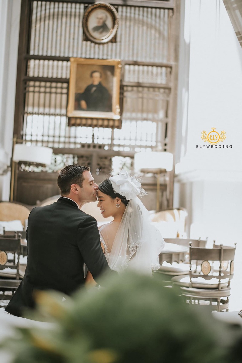 Chuyện tình Việt - Mỹ

Vợ chồng với nhau là duyên số, là định mệnh, có ai tin điều đó ko?

Em đã từng chủ động huỷ hôn vào phút chót, dù đám cưới sắp diễn ra. Lúc đó em đã 33 tuổi. Không nhiều người có đủ dũng cảm để chia tay bạn trai ở cái tuổi đó. Áp lực từ phía gia đình, từ xã hội, ai cũng mong đợi đám cưới ấy diễn ra. Bạn trai cũ của em là người Pháp, có công việc tốt, thu nhập ổn. Hai đứa nhìn đẹp đôi, ai cũng bảo vậy (anh ta cao trên 1,9m, còn em 1,73m). Tuy nhiên càng ngày em càng nhận ra hai đứa có sự khác biệt rất lớn về tính cách và cách sống. Em là người luôn vui vẻ thân thiện với mọi người còn anh ta rất hay phàn nàn và rất dễ nóng giận. Em là người hào phóng, chi tiêu rộng rãi còn anh ta thì lại rất chặt chẽ theo đúng kiểu đàn ông châu Âu. Khi em nói chia tay, anh ta khóc lóc, đau khổ, đêm nào cũng đến đứng trc cửa nhà em tới 2-3 giờ sáng, dù em ko mở cửa, còn đạp xe cả trăm cây số về tận quê em để chứng tỏ tấm chân tình, ngày nào cũng cả trăm tin nhắn, cuộc gọi để năn nỉ...Thế nhưng tính em vốn quyết đoán, đã nói là làm, muốn giũ thì phải phũ. Em nhận ra e k yêu anh ta nhiều. Nếu vẫn cố đám cưới, gia đình em sẽ vui nhưng đổi lại, em k thấy hạnh phúc. Nếu không cưới thì thấy có lỗi với gia đình. Còn cưới thì thấy có lỗi với bản thân. Rồi em cũng quyết định 1 lần dám sống vì bản thân. Vài tháng năn nỉ em quay lại k đc thì cuối cùng anh ta cũng từ bỏ. Cũng nhờ dám bỏ anh ta vào phút chót như vậy, định mệnh đã đưa em gặp chồng em bây giờ, một người đàn ông thành đạt, hào phóng và hết sức yêu chiều vợ.

Càng ngày càng tin vào số phận, mọi thứ như sự sắp đặt của ông trời vậy. Cả anh và em đều ko thích cs hôn nhân. Trc khi gặp nhau, anh vẫn bảo, anh k thích kết hôn, công việc của anh quá bận rộn và anh thấy con cái thật là phiền phức. Lần đầu gặp, hai đứa nói chuyện với nhau quá hợp, cười như ma làm. Đến lúc phải về, bỗng dưng anh hỏi “sau này nếu có kết hôn thì em muốn tổ chức đám cưới ở đâu”. Em chỉ bảo “Marriott Phú Quốc” rồi đi về. Đến lần gặp thứ 2, ăn tối xong, anh tỏ ra cực kì nghiêm túc “anh nghĩ là anh đã sẵn sàng cho cs gia đình. Em có sẵn sàng làm mẹ những đứa con của anh ko?”. Trời ơi, ta nói fast and furious đúng kiểu phim Mỹ. Lúc ấy shock quá, với lại nhanh quá nên bảo cho em thêm thời gian đi. Lúc tiễn anh ra máy bay về lại châu Âu, anh lại bảo “anh muốn được sống cùng em phần đời còn lại. Bất cứ khi nào em muốn sang Ireland thăm anh, hãy nói với anh, anh sẽ mua vé cho em”. Rồi anh đi, vừa qua cửa an ninh, đã thấy tin nhắn của anh. Anh nói anh muốn khóc vì lần đầu tiên anh cảm thấy hụt hẫng vì phải xa 1 người, “anh nhận ra anh cần em biết bao nhiêu”. Rồi từ đó, hai đứa bắt đầu yêu xa. Anh người Mỹ nhưng đag làm dự án ở châu Âu. Giáng sinh vừa rồi, anh muốn đưa em về ra mắt bố mẹ. Tuy nhiên, phút chót, em bị từ chối visa Mỹ mặc dù lịch sử du lịch tốt (hộ chiếu đi 26 nước), tài chính tốt. Tới lúc đó, cay cú quá mới bảo “thôi mình cưới đi”. Thế là anh mừng lắm, anh bảo “cả gia đình anh và bạn bè đều quá shock khi biết anh sắp kết hôn”. Giờ lại thấy cần phải cảm ơn cô viên chức Mỹ vì đã đánh trượt visa, nếu ko sẽ chẳng có động lực để kết hôn đâu.

Cho tới giờ, đôi lúc vẫn ngỡ ngàng, ko nghĩ sẽ có ngày trở thành cô dâu. Mọi người thường bảo, mọi cô gái đều mong muốn khoác lên mình chiếc áo cưới, có lẽ điều này k đúng lắm với em. Người thân hay bạn bè thân thiết với em đều hiểu em là đứa rất sợ cs hôn nhân và gần như trong đầu k hề có ý tưởng sẽ lấy chồng.Em vẫn từng nói, nếu có ngày em cưới, thì đó k phải là điều e muốn mà đơn giản chỉ là muốn cho bố mẹ e vui. Em là đứa có tính cách ngông cuồng, luôn làm điều mình muốn, luôn đi ngược định kiến và những giá trị xã hội đã lỗi thời. Thế nhưng có 1 điều k thể làm đc, đó là: Ko thể làm bố mẹ buồn. Người ta nói “dao sắc k gọt đc chuôi” là vậy. Cuộc đời con người chỉ có 2 món nợ lớn nhất: 1 là với người sinh ra mình, 2 là với người mình sinh ra. Chừng nào em còn chưa lập gđ, khi ấy bố mẹ e còn chưa yên tâm, dù rằng cs vật chất và tinh thần của e đều đầy đủ. Rồi bỗng 1 ngày, con bạn thân kể về sự ra đi đột ngột của bố bạn ấy, bỗng chợt nghĩ “bố mẹ mình cũng già rồi, chẳng biết họ còn sống đv bao lâu nữa, nếu có thể làm cho họ vui thì tại sao lại ko cố gắng”. Vậy là đồng ý cưới. Đc cái anh chồng cũng hiểu tính nên rất chiều, mọi giấy tờ anh tự tìm hiểu và tự chuẩn bị mọi thứ. Chừng nào em vẫn chưa kí vào giấy là anh vẫn lo em sẽ đổi ý. Cuối cùng thì sau gần 2 tháng lo giấy tờ, thủ tục, hai đứa cũng có đc giấy đăng kí kết hôn và giờ em đang mang bầu đứa con đầu lòng ở tuổi 34.

Thế nên phụ nữ cứ đẹp, tự tin và kiêu hãnh lên nhé. Ở đâu đó luôn có 1 người đang chờ đợi chúng ta. “Standing alone doesn’t mean that i’m alone. It means i’m strong enough to handle everything by myself”. Đúng người, đúng thời điểm mới là quan trọng. Và đừng ngại bắt đầu lại khi thấy mối quan hệ đó ko ổn. Suy cho cùng, đích đến của chúng ta là HẠNH PHÚC. Trong một mối quan hệ, bất cứ khi nào bạn thấy không ổn có nghĩa rằng nó không ổn. Hãy tin vào cảm giác của mình.

P/s: Đây là hình cưới của bọn em chụp tại Ireland và Phú Quốc. Hôm chụp ở Ireland, thời tiết ngoài trời là 2oC (feel like -2oC) nên chỉ chụp vội đc vài tấm, lạnh cóng k cười nổi luôn.
Em 34, anh 44, cả hai đều kết hôn lần đầu.

Nguồn: Lyly Ha Nguyễn