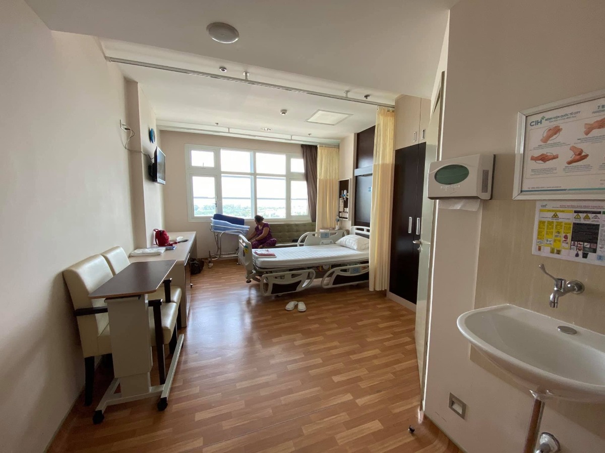REVIEW SINH TẠI QUỐC TẾ CITY

Dạo này thấy có nhiều mom hỏi Cih nên mình cũng xin phép được review sơ sơ chuyến đi đẻ của mình.
Mình khám thai định kỳ ở Sih và tính sinh ở Sih luôn (m đã có 1 bài review khá dài về khám thai ở Sih), nhưng vì một số lý do mà vào phút gần chót 2vc quyết lại sẽ chọn Cih để đẻ.
38w mình khám thử tại Cih thì được hỏi luôn có sinh ở đây không để họ làm hồ sơ sinh, chi phí khám và siêu âm tầm 1tr + làm các xét nghiệm trước sinh hơn 4tr, tổng thiệt hại hơn 5tr.
39w mình tái khám theo lịch và hẹn bác sĩ ngày giờ mổ, được nhiều người mách bác Xuyến trưởng khoa nên m cũng theo bác. Bác rất nhẹ nhàng, dễ thương, nhiệt tình lắm ạ. M muốn mổ vào 15h bác ok ngay và dặn dò m sáng 7h ăn sáng, 8h nhập viện từ đó không được ăn uống gì.
39w4d mình vào viện làm các thủ tục, phòng ở đây tính tiền từ 12h trưa nhưng bv cho m nhận phòng luôn không phải đợi tới 12h, làm thủ tục nhập viện xong m được điều dưỡng cho đo tim thai rồi dẫn lên nhận phòng tầm 9h hơn. Sau đó các cô hộ lý vào phát đồ, hướng dẫn sử dụng phòng ốc, cần gì bấm chuông gọi, trong toilet cũng có chuông nếu chóng mặt chỉ cần bấm là có người vô đỡ. Bv có cho 1 bịch bỉm nhỏ Bobby, 1 bịch bvs Mama, 1 túi quần lót giấy, mấy mom có thể chuẩn bị thêm nếu sợ thiếu nhất là bỉm không đủ đâu nhé! Có bình thuỷ đựng nước nóng để cho mẹ uống, mỗi ngày phát 1c nước khoáng 1L nếu uống không đủ có chỗ hứng nước thêm vô. Đặc biệt cho đăng ký được 2 người ở lại dù mình đẻ phải mùa dịch cao điểm các bv khác đều được chỉ 1 người chăm mà mình có mẹ và bà vú. Phòng m đăng ký là phòng đơn tiêu chuẩn giá 2tr6/ngày (nếu ai không ăn là 2tr3). Bình sữa của bé thì phải gửi ở phòng các cô điều dưỡng tiệt trùng và pha chứ họ không cho m pha ạ. Nên đem theo vài cái bình để phòng các cô chưa tiệt trùng kịp mà em bé đòi ăn thì còn có mà pha ngay. Như bé nhà mình đẻ ra đã háu ăn, chưa có sữa kịp là nó gào lên rất kinh.
Kể tiếp chuyện đi đẻ, sau khi được phát đồ, hướng dẫn phòng ốc...thì m được kêu đi tắm được cạo vùng kín rồi đặt đường truyền nước, đo cơn gò tim thai em bé và nằm chờ tới 14h30 sẽ được đẩy đi mổ.
Ở Cih mổ được cho người nhà vào nhưng chồng mình sợ cảnh mổ xẻ không dám vào 🤣. 
14h30 mình được đẩy đi, xà quần tới 15h17 mới chính thức vô phòng mổ, lúc này bác Xuyến chưa tới, ekip mổ chuẩn bị mọi thứ sẵn sàng, rất đông các bạn trẻ trẻ không à, nam nữ có đủ, có 1 bạn phụ trách nhiệm vụ giải thích hay sao á lúc nào cũng đứng trước đầu mình giải thích các bước nói chuyện rất nhẹ nhàng dễ thương, là 1 bạn nam. 
Tới khúc gây tê cũng không đáng sợ mấy, như tiêm ngừa bình thường thôi, tiêm xong tê tê khá là nhanh, cái màn che căng lên, ở dưới mần gì không biết luôn 🤣, hai tay dạng ra 2 bên, thuốc tê càng ngấm m bị tác dụng phụ là run, không lạnh lắm mà run cầm cập luôn các mom à, các bạn ekip cứ hỏi m có lạnh không, có máy sưởi thổi vô trong lúc mổ nhưng m chỉ thấy run, bạn nam đứng trên đầu mình kêu mình hít sâu thở đều, hỏi hang m liên tục. 
Tiêm được chút xíu bác Xuyến vô mổ cho m, chỉ thấy cái bụng bị lắc qua lắc lại, không cảm nhận được gì, bạn ekip nam đứng trên đầu vẫn liên tục trấn an, giải thích, hướng dẫn hít thở thấy cưng lắm. 
Được chút xíu xiu nghe bác sĩ nói ra rồi ra rồi m mới biết là mổ rồi chứ trong lúc mổ chỉ thấy bụng bị lắc qua lại. Em bé ra mà chưa nghe khóc luôn, m mới hỏi "sao chưa nghe em bé khóc", bác sĩ kêu "khóc không nên lời luôn", rồi nghe bác sĩ nói thêm "khóc đi, khóc đi", sau đó là tiếng oe oe của con vang lên, nước mắt mình cũng chảy theo, bạn ekip nam trên đầu m lại tiếp tục động viên, kêu m không được khóc, nói chuyện nhẹ nhàng dễ thương lắm luôn. (M không biết mấy bạn trong ekip mổ phụ bác sĩ gọi bằng danh xưng gì nên tạm gọi vậy nha)
Em bé bắt ra xong được kề da với mẹ, ẻm khóc oe oe mà đặt lên người mẹ cái nằm im ru, cảm xúc thiên liêng lắm luôn chắc mấy mom trải qua rồi ai cũng hiểu. 
Kề da được chừng 5-10ph gì à, em bé được mang đi, lúc này thì mẹ được khâu vết mổ, chuyện em bé nghe ba nó kể tiếp. Ẻm được đem ra người nhà chỉ được cho ba đi theo xem, ẻm được đo nhịp tim rồi để vô cái máy làm ấm... nghe ba ẻm kể sơ sơ vậy thôi, xong kiểm tra một lúc thì em bé đưa về phòng trước trong khi mẹ nằm hồi sức. 
Quay lại kể chiện mẹ nằm hồi sức, khâu và lau chùi xong xui người ta mới bỏ cái màn che ra thành thử từ lúc gây tê xong ai mần gì mần mẹ không hay biết chi tới lúc xong hết. Mẹ được đẩy ra bên ngoài nằm hồi sức theo dõi tầm 2 tiếng. Tác dụng phụ của thuốc gây tê vẫn làm mình run cầm cập mà cơ địa m không bị lạnh nha, rồi đột nhiên cơn buồn nôn ập tới, sau khi nôn mấy phát không ra được gì thì hết run cũng hết buồn nôn luôn, lúc nôn có người cầm thau kê vô kế bên cho m nôn ạ. Thuốc tê dần dần tan, người m cũng càng lúc càng nóng lên, m phải đẩy mền xuống một nửa chỉ đắp cái áo bệnh viện, m còn nói nóng quá mấy bạn điều dưỡng phải giải thích máy lạnh trung tâm hông chỉnh cho m mát thêm được 🤣. Cái này là do cơ địa nha vì m nằm được lúc có một mom khác cũng mổ ra nằm hồi sức kế bên lạnh cầm cập phải chạy máy sưởi. 
Xong 2 tiếng m được đẩy về phòng với em bé, không được nằm cao đầu tới sáng nên hơi khó chịu tí, vết mổ đau nhưng vẫn trong sức chịu đựng của m được, ráng nằm nghiêng qua cho em bé bú sữa non đầu đời. Nghe nói ẻm khóc nãy giờ đòi bú, bú được tí sữa non ẻm phê phê im ru, may sao ở đây mổ hồi sức có 2 tiếng à, chứ bên Sih tư vấn m hồi sức 6 tiếng lận nè.
Tối đó đau vết mổ nhưng m vẫn nghiêng qua lại cho bé bú mỗi lần bé e e lên. Sáng hôm sau m được rút ống thông tiểu và được dặn dò tập đi, mọi thứ thấy cũng trong sức chịu đựng được, không đau thấu trời xanh như nhiều mom diễn tả đẻ mổ, với thuốc giảm đau nhét ngày 2v nên thấy cũng êm ái ạ. 
Nằm viện 4 ngày mỗi ngày đều có bác sĩ sản vào thăm khám mẹ và vết mổ, bác sĩ nhi thăm khám bé, điều dưỡng đo huyết áp, phát thuốc, đặt thuốc, đo nhiệt độ mẹ, bé... Mỗi sáng em bé được đẩy đi tắm. Ga giường thay mỗi ngày, dọn rác 2 lần/ngày, mẹ được phát 1 nắp thảo dược người Dao đỏ để pha lau mình. Vết mổ ở đây dán keo sinh học, thẩm mĩ, sạch sẽ, đẹp đẽ luôn ạ.
Sáng hôm xuất viện mẹ đi siêu âm lại có hộ lý đẩy từ phòng bệnh lầu 9 tới phòng siêu âm lầu 2. Xuất viện có xe chất hành lý, mẹ cũng được hộ lý đẩy xe đi từ phòng bệnh ra tới cổng xe đón, còn hướng dẫn người nào phụ trách bồng em bé lên xe, hộ lý chuyển em bé cho, mẹ và bé lên xe hết mới hết nhiệm vụ. 
Lúc gần xuất viện có nhân viên quản lý vào hỏi ý kiến chất lượng, góp ý, rồi hỏi có ai thái độ hay có ý muốn bồi dưỡng không. 
Tổng thiệt hại chuyến đi đẻ phòng đơn tiêu chuẩn 2tr6 thêm 2 người ở lại của mình hết 43tr + 5tr xét nghiệm trước sinh. Mình không lấy thuốc bổ sau sinh của bệnh viện và bé mình ổn nên không phát sinh thêm nhiều chi phí như nằm lồng kính hay chiếu đèn vàng da...
Điểm trừ nhẹ là thủ tục xuất viện làm hơi lâu, 11h báo m chuẩn bị mà mãi tới 2h chiều mới xong cho m, với cơm không ngon lắm. Còn lại mọi thứ đều hài lòng. Đời có mấy lần đẻ nên ráng đi đẻ thoải mái tí ạ chứ m sợ cảnh y tá nạt nộ sản phụ lắm!
Tóm lại đẻ mổ với mình không đáng sợ như nhiều mom nói đâu ạ! 
Mom nào còn thắc mắc gì m chia sẽ được thì cmt hoặc inbox cho m nhé!
Edit: thêm 1 điểm trừ nhẹ là bv không có danh sách đồ mang theo cho mẹ và bé như bên sih có in ra danh sách tư vấn kĩ lắm nè, bên này nói miệng sơ sơ à làm ox m ngày nào cũng phải tiếp tế đồ linh tinh, mấy bạn ở tỉnh ở xa sẽ hơi bất tiện nhưng bù lại đối diện là Aeon mall to đùng, qua mua đồ cũng đỡ.
Ví dụ như phát 1 nắp thuốc người Dao đỏ để lau người mà không có cái thau để pha mẹ m phải chạy qua siêu thị để mua nè.
Rồi m có chuẩn bị khăn tắm to để lau người và quấn bé với khăn sữa nhỏ để tắm mà mấy cô tắm đòi tắm khăn trung nên mẹ m phải qua siêu thị mua nữa.
Mấy này đáng ra phải có danh sách để chuẩn bị trước chứ.
Nên đem theo vài cái móc để đôi khi cần phơi khăn sữa, khăn tắm bé nhất là đẻ mổ nằm viện lâu như m.

Nguồn: Từ Ngọc Ánh