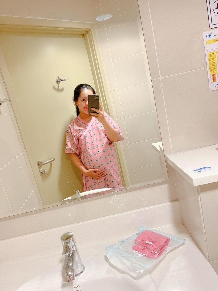 REVIEW SINH TẠI QUỐC TẾ CITY

Dạo này thấy có nhiều mom hỏi Cih nên mình cũng xin phép được review sơ sơ chuyến đi đẻ của mình.
Mình khám thai định kỳ ở Sih và tính sinh ở Sih luôn (m đã có 1 bài review khá dài về khám thai ở Sih), nhưng vì một số lý do mà vào phút gần chót 2vc quyết lại sẽ chọn Cih để đẻ.
38w mình khám thử tại Cih thì được hỏi luôn có sinh ở đây không để họ làm hồ sơ sinh, chi phí khám và siêu âm tầm 1tr + làm các xét nghiệm trước sinh hơn 4tr, tổng thiệt hại hơn 5tr.
39w mình tái khám theo lịch và hẹn bác sĩ ngày giờ mổ, được nhiều người mách bác Xuyến trưởng khoa nên m cũng theo bác. Bác rất nhẹ nhàng, dễ thương, nhiệt tình lắm ạ. M muốn mổ vào 15h bác ok ngay và dặn dò m sáng 7h ăn sáng, 8h nhập viện từ đó không được ăn uống gì.
39w4d mình vào viện làm các thủ tục, phòng ở đây tính tiền từ 12h trưa nhưng bv cho m nhận phòng luôn không phải đợi tới 12h, làm thủ tục nhập viện xong m được điều dưỡng cho đo tim thai rồi dẫn lên nhận phòng tầm 9h hơn. Sau đó các cô hộ lý vào phát đồ, hướng dẫn sử dụng phòng ốc, cần gì bấm chuông gọi, trong toilet cũng có chuông nếu chóng mặt chỉ cần bấm là có người vô đỡ. Bv có cho 1 bịch bỉm nhỏ Bobby, 1 bịch bvs Mama, 1 túi quần lót giấy, mấy mom có thể chuẩn bị thêm nếu sợ thiếu nhất là bỉm không đủ đâu nhé! Có bình thuỷ đựng nước nóng để cho mẹ uống, mỗi ngày phát 1c nước khoáng 1L nếu uống không đủ có chỗ hứng nước thêm vô. Đặc biệt cho đăng ký được 2 người ở lại dù mình đẻ phải mùa dịch cao điểm các bv khác đều được chỉ 1 người chăm mà mình có mẹ và bà vú. Phòng m đăng ký là phòng đơn tiêu chuẩn giá 2tr6/ngày (nếu ai không ăn là 2tr3). Bình sữa của bé thì phải gửi ở phòng các cô điều dưỡng tiệt trùng và pha chứ họ không cho m pha ạ. Nên đem theo vài cái bình để phòng các cô chưa tiệt trùng kịp mà em bé đòi ăn thì còn có mà pha ngay. Như bé nhà mình đẻ ra đã háu ăn, chưa có sữa kịp là nó gào lên rất kinh.
Kể tiếp chuyện đi đẻ, sau khi được phát đồ, hướng dẫn phòng ốc...thì m được kêu đi tắm được cạo vùng kín rồi đặt đường truyền nước, đo cơn gò tim thai em bé và nằm chờ tới 14h30 sẽ được đẩy đi mổ.
Ở Cih mổ được cho người nhà vào nhưng chồng mình sợ cảnh mổ xẻ không dám vào 🤣. 
14h30 mình được đẩy đi, xà quần tới 15h17 mới chính thức vô phòng mổ, lúc này bác Xuyến chưa tới, ekip mổ chuẩn bị mọi thứ sẵn sàng, rất đông các bạn trẻ trẻ không à, nam nữ có đủ, có 1 bạn phụ trách nhiệm vụ giải thích hay sao á lúc nào cũng đứng trước đầu mình giải thích các bước nói chuyện rất nhẹ nhàng dễ thương, là 1 bạn nam. 
Tới khúc gây tê cũng không đáng sợ mấy, như tiêm ngừa bình thường thôi, tiêm xong tê tê khá là nhanh, cái màn che căng lên, ở dưới mần gì không biết luôn 🤣, hai tay dạng ra 2 bên, thuốc tê càng ngấm m bị tác dụng phụ là run, không lạnh lắm mà run cầm cập luôn các mom à, các bạn ekip cứ hỏi m có lạnh không, có máy sưởi thổi vô trong lúc mổ nhưng m chỉ thấy run, bạn nam đứng trên đầu mình kêu mình hít sâu thở đều, hỏi hang m liên tục. 
Tiêm được chút xíu bác Xuyến vô mổ cho m, chỉ thấy cái bụng bị lắc qua lắc lại, không cảm nhận được gì, bạn ekip nam đứng trên đầu vẫn liên tục trấn an, giải thích, hướng dẫn hít thở thấy cưng lắm. 
Được chút xíu xiu nghe bác sĩ nói ra rồi ra rồi m mới biết là mổ rồi chứ trong lúc mổ chỉ thấy bụng bị lắc qua lại. Em bé ra mà chưa nghe khóc luôn, m mới hỏi "sao chưa nghe em bé khóc", bác sĩ kêu "khóc không nên lời luôn", rồi nghe bác sĩ nói thêm "khóc đi, khóc đi", sau đó là tiếng oe oe của con vang lên, nước mắt mình cũng chảy theo, bạn ekip nam trên đầu m lại tiếp tục động viên, kêu m không được khóc, nói chuyện nhẹ nhàng dễ thương lắm luôn. (M không biết mấy bạn trong ekip mổ phụ bác sĩ gọi bằng danh xưng gì nên tạm gọi vậy nha)
Em bé bắt ra xong được kề da với mẹ, ẻm khóc oe oe mà đặt lên người mẹ cái nằm im ru, cảm xúc thiên liêng lắm luôn chắc mấy mom trải qua rồi ai cũng hiểu. 
Kề da được chừng 5-10ph gì à, em bé được mang đi, lúc này thì mẹ được khâu vết mổ, chuyện em bé nghe ba nó kể tiếp. Ẻm được đem ra người nhà chỉ được cho ba đi theo xem, ẻm được đo nhịp tim rồi để vô cái máy làm ấm... nghe ba ẻm kể sơ sơ vậy thôi, xong kiểm tra một lúc thì em bé đưa về phòng trước trong khi mẹ nằm hồi sức. 
Quay lại kể chiện mẹ nằm hồi sức, khâu và lau chùi xong xui người ta mới bỏ cái màn che ra thành thử từ lúc gây tê xong ai mần gì mần mẹ không hay biết chi tới lúc xong hết. Mẹ được đẩy ra bên ngoài nằm hồi sức theo dõi tầm 2 tiếng. Tác dụng phụ của thuốc gây tê vẫn làm mình run cầm cập mà cơ địa m không bị lạnh nha, rồi đột nhiên cơn buồn nôn ập tới, sau khi nôn mấy phát không ra được gì thì hết run cũng hết buồn nôn luôn, lúc nôn có người cầm thau kê vô kế bên cho m nôn ạ. Thuốc tê dần dần tan, người m cũng càng lúc càng nóng lên, m phải đẩy mền xuống một nửa chỉ đắp cái áo bệnh viện, m còn nói nóng quá mấy bạn điều dưỡng phải giải thích máy lạnh trung tâm hông chỉnh cho m mát thêm được 🤣. Cái này là do cơ địa nha vì m nằm được lúc có một mom khác cũng mổ ra nằm hồi sức kế bên lạnh cầm cập phải chạy máy sưởi. 
Xong 2 tiếng m được đẩy về phòng với em bé, không được nằm cao đầu tới sáng nên hơi khó chịu tí, vết mổ đau nhưng vẫn trong sức chịu đựng của m được, ráng nằm nghiêng qua cho em bé bú sữa non đầu đời. Nghe nói ẻm khóc nãy giờ đòi bú, bú được tí sữa non ẻm phê phê im ru, may sao ở đây mổ hồi sức có 2 tiếng à, chứ bên Sih tư vấn m hồi sức 6 tiếng lận nè.
Tối đó đau vết mổ nhưng m vẫn nghiêng qua lại cho bé bú mỗi lần bé e e lên. Sáng hôm sau m được rút ống thông tiểu và được dặn dò tập đi, mọi thứ thấy cũng trong sức chịu đựng được, không đau thấu trời xanh như nhiều mom diễn tả đẻ mổ, với thuốc giảm đau nhét ngày 2v nên thấy cũng êm ái ạ. 
Nằm viện 4 ngày mỗi ngày đều có bác sĩ sản vào thăm khám mẹ và vết mổ, bác sĩ nhi thăm khám bé, điều dưỡng đo huyết áp, phát thuốc, đặt thuốc, đo nhiệt độ mẹ, bé... Mỗi sáng em bé được đẩy đi tắm. Ga giường thay mỗi ngày, dọn rác 2 lần/ngày, mẹ được phát 1 nắp thảo dược người Dao đỏ để pha lau mình. Vết mổ ở đây dán keo sinh học, thẩm mĩ, sạch sẽ, đẹp đẽ luôn ạ.
Sáng hôm xuất viện mẹ đi siêu âm lại có hộ lý đẩy từ phòng bệnh lầu 9 tới phòng siêu âm lầu 2. Xuất viện có xe chất hành lý, mẹ cũng được hộ lý đẩy xe đi từ phòng bệnh ra tới cổng xe đón, còn hướng dẫn người nào phụ trách bồng em bé lên xe, hộ lý chuyển em bé cho, mẹ và bé lên xe hết mới hết nhiệm vụ. 
Lúc gần xuất viện có nhân viên quản lý vào hỏi ý kiến chất lượng, góp ý, rồi hỏi có ai thái độ hay có ý muốn bồi dưỡng không. 
Tổng thiệt hại chuyến đi đẻ phòng đơn tiêu chuẩn 2tr6 thêm 2 người ở lại của mình hết 43tr + 5tr xét nghiệm trước sinh. Mình không lấy thuốc bổ sau sinh của bệnh viện và bé mình ổn nên không phát sinh thêm nhiều chi phí như nằm lồng kính hay chiếu đèn vàng da...
Điểm trừ nhẹ là thủ tục xuất viện làm hơi lâu, 11h báo m chuẩn bị mà mãi tới 2h chiều mới xong cho m, với cơm không ngon lắm. Còn lại mọi thứ đều hài lòng. Đời có mấy lần đẻ nên ráng đi đẻ thoải mái tí ạ chứ m sợ cảnh y tá nạt nộ sản phụ lắm!
Tóm lại đẻ mổ với mình không đáng sợ như nhiều mom nói đâu ạ! 
Mom nào còn thắc mắc gì m chia sẽ được thì cmt hoặc inbox cho m nhé!
Edit: thêm 1 điểm trừ nhẹ là bv không có danh sách đồ mang theo cho mẹ và bé như bên sih có in ra danh sách tư vấn kĩ lắm nè, bên này nói miệng sơ sơ à làm ox m ngày nào cũng phải tiếp tế đồ linh tinh, mấy bạn ở tỉnh ở xa sẽ hơi bất tiện nhưng bù lại đối diện là Aeon mall to đùng, qua mua đồ cũng đỡ.
Ví dụ như phát 1 nắp thuốc người Dao đỏ để lau người mà không có cái thau để pha mẹ m phải chạy qua siêu thị để mua nè.
Rồi m có chuẩn bị khăn tắm to để lau người và quấn bé với khăn sữa nhỏ để tắm mà mấy cô tắm đòi tắm khăn trung nên mẹ m phải qua siêu thị mua nữa.
Mấy này đáng ra phải có danh sách để chuẩn bị trước chứ.
Nên đem theo vài cái móc để đôi khi cần phơi khăn sữa, khăn tắm bé nhất là đẻ mổ nằm viện lâu như m.

Nguồn: Từ Ngọc Ánh