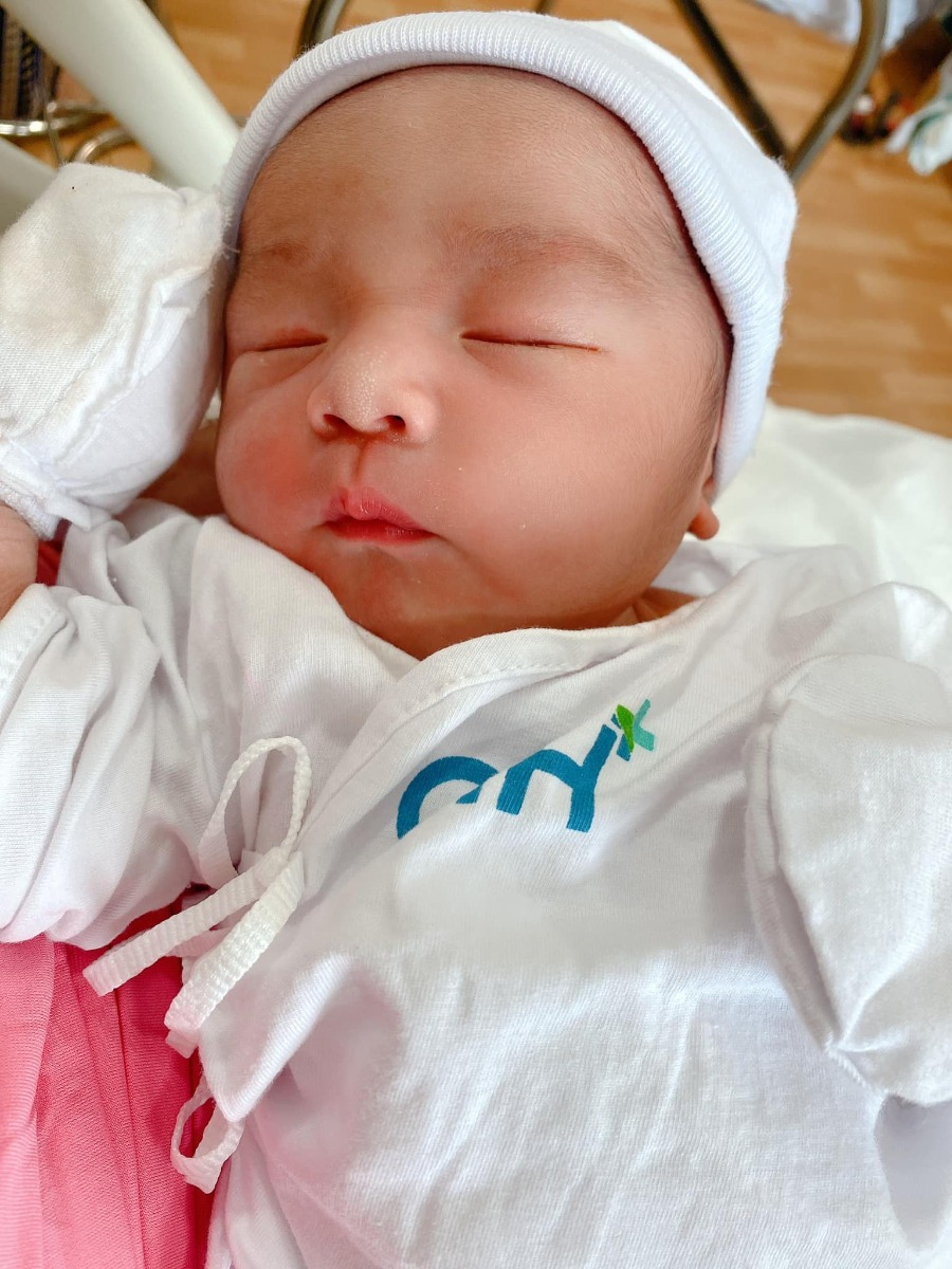 REVIEW SINH TẠI QUỐC TẾ CITY

Dạo này thấy có nhiều mom hỏi Cih nên mình cũng xin phép được review sơ sơ chuyến đi đẻ của mình.
Mình khám thai định kỳ ở Sih và tính sinh ở Sih luôn (m đã có 1 bài review khá dài về khám thai ở Sih), nhưng vì một số lý do mà vào phút gần chót 2vc quyết lại sẽ chọn Cih để đẻ.
38w mình khám thử tại Cih thì được hỏi luôn có sinh ở đây không để họ làm hồ sơ sinh, chi phí khám và siêu âm tầm 1tr + làm các xét nghiệm trước sinh hơn 4tr, tổng thiệt hại hơn 5tr.
39w mình tái khám theo lịch và hẹn bác sĩ ngày giờ mổ, được nhiều người mách bác Xuyến trưởng khoa nên m cũng theo bác. Bác rất nhẹ nhàng, dễ thương, nhiệt tình lắm ạ. M muốn mổ vào 15h bác ok ngay và dặn dò m sáng 7h ăn sáng, 8h nhập viện từ đó không được ăn uống gì.
39w4d mình vào viện làm các thủ tục, phòng ở đây tính tiền từ 12h trưa nhưng bv cho m nhận phòng luôn không phải đợi tới 12h, làm thủ tục nhập viện xong m được điều dưỡng cho đo tim thai rồi dẫn lên nhận phòng tầm 9h hơn. Sau đó các cô hộ lý vào phát đồ, hướng dẫn sử dụng phòng ốc, cần gì bấm chuông gọi, trong toilet cũng có chuông nếu chóng mặt chỉ cần bấm là có người vô đỡ. Bv có cho 1 bịch bỉm nhỏ Bobby, 1 bịch bvs Mama, 1 túi quần lót giấy, mấy mom có thể chuẩn bị thêm nếu sợ thiếu nhất là bỉm không đủ đâu nhé! Có bình thuỷ đựng nước nóng để cho mẹ uống, mỗi ngày phát 1c nước khoáng 1L nếu uống không đủ có chỗ hứng nước thêm vô. Đặc biệt cho đăng ký được 2 người ở lại dù mình đẻ phải mùa dịch cao điểm các bv khác đều được chỉ 1 người chăm mà mình có mẹ và bà vú. Phòng m đăng ký là phòng đơn tiêu chuẩn giá 2tr6/ngày (nếu ai không ăn là 2tr3). Bình sữa của bé thì phải gửi ở phòng các cô điều dưỡng tiệt trùng và pha chứ họ không cho m pha ạ. Nên đem theo vài cái bình để phòng các cô chưa tiệt trùng kịp mà em bé đòi ăn thì còn có mà pha ngay. Như bé nhà mình đẻ ra đã háu ăn, chưa có sữa kịp là nó gào lên rất kinh.
Kể tiếp chuyện đi đẻ, sau khi được phát đồ, hướng dẫn phòng ốc...thì m được kêu đi tắm được cạo vùng kín rồi đặt đường truyền nước, đo cơn gò tim thai em bé và nằm chờ tới 14h30 sẽ được đẩy đi mổ.
Ở Cih mổ được cho người nhà vào nhưng chồng mình sợ cảnh mổ xẻ không dám vào 🤣. 
14h30 mình được đẩy đi, xà quần tới 15h17 mới chính thức vô phòng mổ, lúc này bác Xuyến chưa tới, ekip mổ chuẩn bị mọi thứ sẵn sàng, rất đông các bạn trẻ trẻ không à, nam nữ có đủ, có 1 bạn phụ trách nhiệm vụ giải thích hay sao á lúc nào cũng đứng trước đầu mình giải thích các bước nói chuyện rất nhẹ nhàng dễ thương, là 1 bạn nam. 
Tới khúc gây tê cũng không đáng sợ mấy, như tiêm ngừa bình thường thôi, tiêm xong tê tê khá là nhanh, cái màn che căng lên, ở dưới mần gì không biết luôn 🤣, hai tay dạng ra 2 bên, thuốc tê càng ngấm m bị tác dụng phụ là run, không lạnh lắm mà run cầm cập luôn các mom à, các bạn ekip cứ hỏi m có lạnh không, có máy sưởi thổi vô trong lúc mổ nhưng m chỉ thấy run, bạn nam đứng trên đầu mình kêu mình hít sâu thở đều, hỏi hang m liên tục. 
Tiêm được chút xíu bác Xuyến vô mổ cho m, chỉ thấy cái bụng bị lắc qua lắc lại, không cảm nhận được gì, bạn ekip nam đứng trên đầu vẫn liên tục trấn an, giải thích, hướng dẫn hít thở thấy cưng lắm. 
Được chút xíu xiu nghe bác sĩ nói ra rồi ra rồi m mới biết là mổ rồi chứ trong lúc mổ chỉ thấy bụng bị lắc qua lại. Em bé ra mà chưa nghe khóc luôn, m mới hỏi "sao chưa nghe em bé khóc", bác sĩ kêu "khóc không nên lời luôn", rồi nghe bác sĩ nói thêm "khóc đi, khóc đi", sau đó là tiếng oe oe của con vang lên, nước mắt mình cũng chảy theo, bạn ekip nam trên đầu m lại tiếp tục động viên, kêu m không được khóc, nói chuyện nhẹ nhàng dễ thương lắm luôn. (M không biết mấy bạn trong ekip mổ phụ bác sĩ gọi bằng danh xưng gì nên tạm gọi vậy nha)
Em bé bắt ra xong được kề da với mẹ, ẻm khóc oe oe mà đặt lên người mẹ cái nằm im ru, cảm xúc thiên liêng lắm luôn chắc mấy mom trải qua rồi ai cũng hiểu. 
Kề da được chừng 5-10ph gì à, em bé được mang đi, lúc này thì mẹ được khâu vết mổ, chuyện em bé nghe ba nó kể tiếp. Ẻm được đem ra người nhà chỉ được cho ba đi theo xem, ẻm được đo nhịp tim rồi để vô cái máy làm ấm... nghe ba ẻm kể sơ sơ vậy thôi, xong kiểm tra một lúc thì em bé đưa về phòng trước trong khi mẹ nằm hồi sức. 
Quay lại kể chiện mẹ nằm hồi sức, khâu và lau chùi xong xui người ta mới bỏ cái màn che ra thành thử từ lúc gây tê xong ai mần gì mần mẹ không hay biết chi tới lúc xong hết. Mẹ được đẩy ra bên ngoài nằm hồi sức theo dõi tầm 2 tiếng. Tác dụng phụ của thuốc gây tê vẫn làm mình run cầm cập mà cơ địa m không bị lạnh nha, rồi đột nhiên cơn buồn nôn ập tới, sau khi nôn mấy phát không ra được gì thì hết run cũng hết buồn nôn luôn, lúc nôn có người cầm thau kê vô kế bên cho m nôn ạ. Thuốc tê dần dần tan, người m cũng càng lúc càng nóng lên, m phải đẩy mền xuống một nửa chỉ đắp cái áo bệnh viện, m còn nói nóng quá mấy bạn điều dưỡng phải giải thích máy lạnh trung tâm hông chỉnh cho m mát thêm được 🤣. Cái này là do cơ địa nha vì m nằm được lúc có một mom khác cũng mổ ra nằm hồi sức kế bên lạnh cầm cập phải chạy máy sưởi. 
Xong 2 tiếng m được đẩy về phòng với em bé, không được nằm cao đầu tới sáng nên hơi khó chịu tí, vết mổ đau nhưng vẫn trong sức chịu đựng của m được, ráng nằm nghiêng qua cho em bé bú sữa non đầu đời. Nghe nói ẻm khóc nãy giờ đòi bú, bú được tí sữa non ẻm phê phê im ru, may sao ở đây mổ hồi sức có 2 tiếng à, chứ bên Sih tư vấn m hồi sức 6 tiếng lận nè.
Tối đó đau vết mổ nhưng m vẫn nghiêng qua lại cho bé bú mỗi lần bé e e lên. Sáng hôm sau m được rút ống thông tiểu và được dặn dò tập đi, mọi thứ thấy cũng trong sức chịu đựng được, không đau thấu trời xanh như nhiều mom diễn tả đẻ mổ, với thuốc giảm đau nhét ngày 2v nên thấy cũng êm ái ạ. 
Nằm viện 4 ngày mỗi ngày đều có bác sĩ sản vào thăm khám mẹ và vết mổ, bác sĩ nhi thăm khám bé, điều dưỡng đo huyết áp, phát thuốc, đặt thuốc, đo nhiệt độ mẹ, bé... Mỗi sáng em bé được đẩy đi tắm. Ga giường thay mỗi ngày, dọn rác 2 lần/ngày, mẹ được phát 1 nắp thảo dược người Dao đỏ để pha lau mình. Vết mổ ở đây dán keo sinh học, thẩm mĩ, sạch sẽ, đẹp đẽ luôn ạ.
Sáng hôm xuất viện mẹ đi siêu âm lại có hộ lý đẩy từ phòng bệnh lầu 9 tới phòng siêu âm lầu 2. Xuất viện có xe chất hành lý, mẹ cũng được hộ lý đẩy xe đi từ phòng bệnh ra tới cổng xe đón, còn hướng dẫn người nào phụ trách bồng em bé lên xe, hộ lý chuyển em bé cho, mẹ và bé lên xe hết mới hết nhiệm vụ. 
Lúc gần xuất viện có nhân viên quản lý vào hỏi ý kiến chất lượng, góp ý, rồi hỏi có ai thái độ hay có ý muốn bồi dưỡng không. 
Tổng thiệt hại chuyến đi đẻ phòng đơn tiêu chuẩn 2tr6 thêm 2 người ở lại của mình hết 43tr + 5tr xét nghiệm trước sinh. Mình không lấy thuốc bổ sau sinh của bệnh viện và bé mình ổn nên không phát sinh thêm nhiều chi phí như nằm lồng kính hay chiếu đèn vàng da...
Điểm trừ nhẹ là thủ tục xuất viện làm hơi lâu, 11h báo m chuẩn bị mà mãi tới 2h chiều mới xong cho m, với cơm không ngon lắm. Còn lại mọi thứ đều hài lòng. Đời có mấy lần đẻ nên ráng đi đẻ thoải mái tí ạ chứ m sợ cảnh y tá nạt nộ sản phụ lắm!
Tóm lại đẻ mổ với mình không đáng sợ như nhiều mom nói đâu ạ! 
Mom nào còn thắc mắc gì m chia sẽ được thì cmt hoặc inbox cho m nhé!
Edit: thêm 1 điểm trừ nhẹ là bv không có danh sách đồ mang theo cho mẹ và bé như bên sih có in ra danh sách tư vấn kĩ lắm nè, bên này nói miệng sơ sơ à làm ox m ngày nào cũng phải tiếp tế đồ linh tinh, mấy bạn ở tỉnh ở xa sẽ hơi bất tiện nhưng bù lại đối diện là Aeon mall to đùng, qua mua đồ cũng đỡ.
Ví dụ như phát 1 nắp thuốc người Dao đỏ để lau người mà không có cái thau để pha mẹ m phải chạy qua siêu thị để mua nè.
Rồi m có chuẩn bị khăn tắm to để lau người và quấn bé với khăn sữa nhỏ để tắm mà mấy cô tắm đòi tắm khăn trung nên mẹ m phải qua siêu thị mua nữa.
Mấy này đáng ra phải có danh sách để chuẩn bị trước chứ.
Nên đem theo vài cái móc để đôi khi cần phơi khăn sữa, khăn tắm bé nhất là đẻ mổ nằm viện lâu như m.

Nguồn: Từ Ngọc Ánh