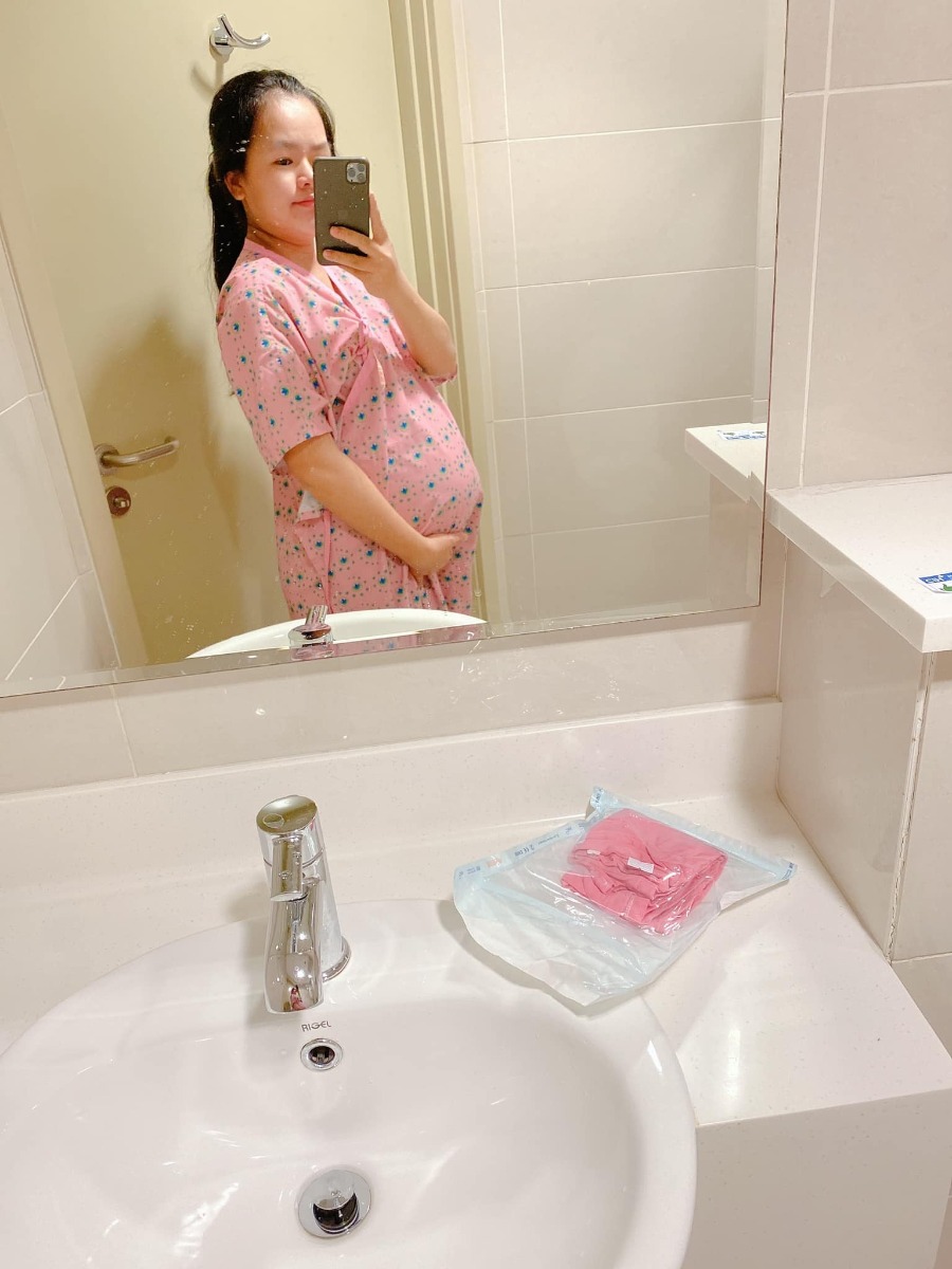 REVIEW SINH TẠI QUỐC TẾ CITY

Dạo này thấy có nhiều mom hỏi Cih nên mình cũng xin phép được review sơ sơ chuyến đi đẻ của mình.
Mình khám thai định kỳ ở Sih và tính sinh ở Sih luôn (m đã có 1 bài review khá dài về khám thai ở Sih), nhưng vì một số lý do mà vào phút gần chót 2vc quyết lại sẽ chọn Cih để đẻ.
38w mình khám thử tại Cih thì được hỏi luôn có sinh ở đây không để họ làm hồ sơ sinh, chi phí khám và siêu âm tầm 1tr + làm các xét nghiệm trước sinh hơn 4tr, tổng thiệt hại hơn 5tr.
39w mình tái khám theo lịch và hẹn bác sĩ ngày giờ mổ, được nhiều người mách bác Xuyến trưởng khoa nên m cũng theo bác. Bác rất nhẹ nhàng, dễ thương, nhiệt tình lắm ạ. M muốn mổ vào 15h bác ok ngay và dặn dò m sáng 7h ăn sáng, 8h nhập viện từ đó không được ăn uống gì.
39w4d mình vào viện làm các thủ tục, phòng ở đây tính tiền từ 12h trưa nhưng bv cho m nhận phòng luôn không phải đợi tới 12h, làm thủ tục nhập viện xong m được điều dưỡng cho đo tim thai rồi dẫn lên nhận phòng tầm 9h hơn. Sau đó các cô hộ lý vào phát đồ, hướng dẫn sử dụng phòng ốc, cần gì bấm chuông gọi, trong toilet cũng có chuông nếu chóng mặt chỉ cần bấm là có người vô đỡ. Bv có cho 1 bịch bỉm nhỏ Bobby, 1 bịch bvs Mama, 1 túi quần lót giấy, mấy mom có thể chuẩn bị thêm nếu sợ thiếu nhất là bỉm không đủ đâu nhé! Có bình thuỷ đựng nước nóng để cho mẹ uống, mỗi ngày phát 1c nước khoáng 1L nếu uống không đủ có chỗ hứng nước thêm vô. Đặc biệt cho đăng ký được 2 người ở lại dù mình đẻ phải mùa dịch cao điểm các bv khác đều được chỉ 1 người chăm mà mình có mẹ và bà vú. Phòng m đăng ký là phòng đơn tiêu chuẩn giá 2tr6/ngày (nếu ai không ăn là 2tr3). Bình sữa của bé thì phải gửi ở phòng các cô điều dưỡng tiệt trùng và pha chứ họ không cho m pha ạ. Nên đem theo vài cái bình để phòng các cô chưa tiệt trùng kịp mà em bé đòi ăn thì còn có mà pha ngay. Như bé nhà mình đẻ ra đã háu ăn, chưa có sữa kịp là nó gào lên rất kinh.
Kể tiếp chuyện đi đẻ, sau khi được phát đồ, hướng dẫn phòng ốc...thì m được kêu đi tắm được cạo vùng kín rồi đặt đường truyền nước, đo cơn gò tim thai em bé và nằm chờ tới 14h30 sẽ được đẩy đi mổ.
Ở Cih mổ được cho người nhà vào nhưng chồng mình sợ cảnh mổ xẻ không dám vào 🤣. 
14h30 mình được đẩy đi, xà quần tới 15h17 mới chính thức vô phòng mổ, lúc này bác Xuyến chưa tới, ekip mổ chuẩn bị mọi thứ sẵn sàng, rất đông các bạn trẻ trẻ không à, nam nữ có đủ, có 1 bạn phụ trách nhiệm vụ giải thích hay sao á lúc nào cũng đứng trước đầu mình giải thích các bước nói chuyện rất nhẹ nhàng dễ thương, là 1 bạn nam. 
Tới khúc gây tê cũng không đáng sợ mấy, như tiêm ngừa bình thường thôi, tiêm xong tê tê khá là nhanh, cái màn che căng lên, ở dưới mần gì không biết luôn 🤣, hai tay dạng ra 2 bên, thuốc tê càng ngấm m bị tác dụng phụ là run, không lạnh lắm mà run cầm cập luôn các mom à, các bạn ekip cứ hỏi m có lạnh không, có máy sưởi thổi vô trong lúc mổ nhưng m chỉ thấy run, bạn nam đứng trên đầu mình kêu mình hít sâu thở đều, hỏi hang m liên tục. 
Tiêm được chút xíu bác Xuyến vô mổ cho m, chỉ thấy cái bụng bị lắc qua lắc lại, không cảm nhận được gì, bạn ekip nam đứng trên đầu vẫn liên tục trấn an, giải thích, hướng dẫn hít thở thấy cưng lắm. 
Được chút xíu xiu nghe bác sĩ nói ra rồi ra rồi m mới biết là mổ rồi chứ trong lúc mổ chỉ thấy bụng bị lắc qua lại. Em bé ra mà chưa nghe khóc luôn, m mới hỏi "sao chưa nghe em bé khóc", bác sĩ kêu "khóc không nên lời luôn", rồi nghe bác sĩ nói thêm "khóc đi, khóc đi", sau đó là tiếng oe oe của con vang lên, nước mắt mình cũng chảy theo, bạn ekip nam trên đầu m lại tiếp tục động viên, kêu m không được khóc, nói chuyện nhẹ nhàng dễ thương lắm luôn. (M không biết mấy bạn trong ekip mổ phụ bác sĩ gọi bằng danh xưng gì nên tạm gọi vậy nha)
Em bé bắt ra xong được kề da với mẹ, ẻm khóc oe oe mà đặt lên người mẹ cái nằm im ru, cảm xúc thiên liêng lắm luôn chắc mấy mom trải qua rồi ai cũng hiểu. 
Kề da được chừng 5-10ph gì à, em bé được mang đi, lúc này thì mẹ được khâu vết mổ, chuyện em bé nghe ba nó kể tiếp. Ẻm được đem ra người nhà chỉ được cho ba đi theo xem, ẻm được đo nhịp tim rồi để vô cái máy làm ấm... nghe ba ẻm kể sơ sơ vậy thôi, xong kiểm tra một lúc thì em bé đưa về phòng trước trong khi mẹ nằm hồi sức. 
Quay lại kể chiện mẹ nằm hồi sức, khâu và lau chùi xong xui người ta mới bỏ cái màn che ra thành thử từ lúc gây tê xong ai mần gì mần mẹ không hay biết chi tới lúc xong hết. Mẹ được đẩy ra bên ngoài nằm hồi sức theo dõi tầm 2 tiếng. Tác dụng phụ của thuốc gây tê vẫn làm mình run cầm cập mà cơ địa m không bị lạnh nha, rồi đột nhiên cơn buồn nôn ập tới, sau khi nôn mấy phát không ra được gì thì hết run cũng hết buồn nôn luôn, lúc nôn có người cầm thau kê vô kế bên cho m nôn ạ. Thuốc tê dần dần tan, người m cũng càng lúc càng nóng lên, m phải đẩy mền xuống một nửa chỉ đắp cái áo bệnh viện, m còn nói nóng quá mấy bạn điều dưỡng phải giải thích máy lạnh trung tâm hông chỉnh cho m mát thêm được 🤣. Cái này là do cơ địa nha vì m nằm được lúc có một mom khác cũng mổ ra nằm hồi sức kế bên lạnh cầm cập phải chạy máy sưởi. 
Xong 2 tiếng m được đẩy về phòng với em bé, không được nằm cao đầu tới sáng nên hơi khó chịu tí, vết mổ đau nhưng vẫn trong sức chịu đựng của m được, ráng nằm nghiêng qua cho em bé bú sữa non đầu đời. Nghe nói ẻm khóc nãy giờ đòi bú, bú được tí sữa non ẻm phê phê im ru, may sao ở đây mổ hồi sức có 2 tiếng à, chứ bên Sih tư vấn m hồi sức 6 tiếng lận nè.
Tối đó đau vết mổ nhưng m vẫn nghiêng qua lại cho bé bú mỗi lần bé e e lên. Sáng hôm sau m được rút ống thông tiểu và được dặn dò tập đi, mọi thứ thấy cũng trong sức chịu đựng được, không đau thấu trời xanh như nhiều mom diễn tả đẻ mổ, với thuốc giảm đau nhét ngày 2v nên thấy cũng êm ái ạ. 
Nằm viện 4 ngày mỗi ngày đều có bác sĩ sản vào thăm khám mẹ và vết mổ, bác sĩ nhi thăm khám bé, điều dưỡng đo huyết áp, phát thuốc, đặt thuốc, đo nhiệt độ mẹ, bé... Mỗi sáng em bé được đẩy đi tắm. Ga giường thay mỗi ngày, dọn rác 2 lần/ngày, mẹ được phát 1 nắp thảo dược người Dao đỏ để pha lau mình. Vết mổ ở đây dán keo sinh học, thẩm mĩ, sạch sẽ, đẹp đẽ luôn ạ.
Sáng hôm xuất viện mẹ đi siêu âm lại có hộ lý đẩy từ phòng bệnh lầu 9 tới phòng siêu âm lầu 2. Xuất viện có xe chất hành lý, mẹ cũng được hộ lý đẩy xe đi từ phòng bệnh ra tới cổng xe đón, còn hướng dẫn người nào phụ trách bồng em bé lên xe, hộ lý chuyển em bé cho, mẹ và bé lên xe hết mới hết nhiệm vụ. 
Lúc gần xuất viện có nhân viên quản lý vào hỏi ý kiến chất lượng, góp ý, rồi hỏi có ai thái độ hay có ý muốn bồi dưỡng không. 
Tổng thiệt hại chuyến đi đẻ phòng đơn tiêu chuẩn 2tr6 thêm 2 người ở lại của mình hết 43tr + 5tr xét nghiệm trước sinh. Mình không lấy thuốc bổ sau sinh của bệnh viện và bé mình ổn nên không phát sinh thêm nhiều chi phí như nằm lồng kính hay chiếu đèn vàng da...
Điểm trừ nhẹ là thủ tục xuất viện làm hơi lâu, 11h báo m chuẩn bị mà mãi tới 2h chiều mới xong cho m, với cơm không ngon lắm. Còn lại mọi thứ đều hài lòng. Đời có mấy lần đẻ nên ráng đi đẻ thoải mái tí ạ chứ m sợ cảnh y tá nạt nộ sản phụ lắm!
Tóm lại đẻ mổ với mình không đáng sợ như nhiều mom nói đâu ạ! 
Mom nào còn thắc mắc gì m chia sẽ được thì cmt hoặc inbox cho m nhé!
Edit: thêm 1 điểm trừ nhẹ là bv không có danh sách đồ mang theo cho mẹ và bé như bên sih có in ra danh sách tư vấn kĩ lắm nè, bên này nói miệng sơ sơ à làm ox m ngày nào cũng phải tiếp tế đồ linh tinh, mấy bạn ở tỉnh ở xa sẽ hơi bất tiện nhưng bù lại đối diện là Aeon mall to đùng, qua mua đồ cũng đỡ.
Ví dụ như phát 1 nắp thuốc người Dao đỏ để lau người mà không có cái thau để pha mẹ m phải chạy qua siêu thị để mua nè.
Rồi m có chuẩn bị khăn tắm to để lau người và quấn bé với khăn sữa nhỏ để tắm mà mấy cô tắm đòi tắm khăn trung nên mẹ m phải qua siêu thị mua nữa.
Mấy này đáng ra phải có danh sách để chuẩn bị trước chứ.
Nên đem theo vài cái móc để đôi khi cần phơi khăn sữa, khăn tắm bé nhất là đẻ mổ nằm viện lâu như m.

Nguồn: Từ Ngọc Ánh
