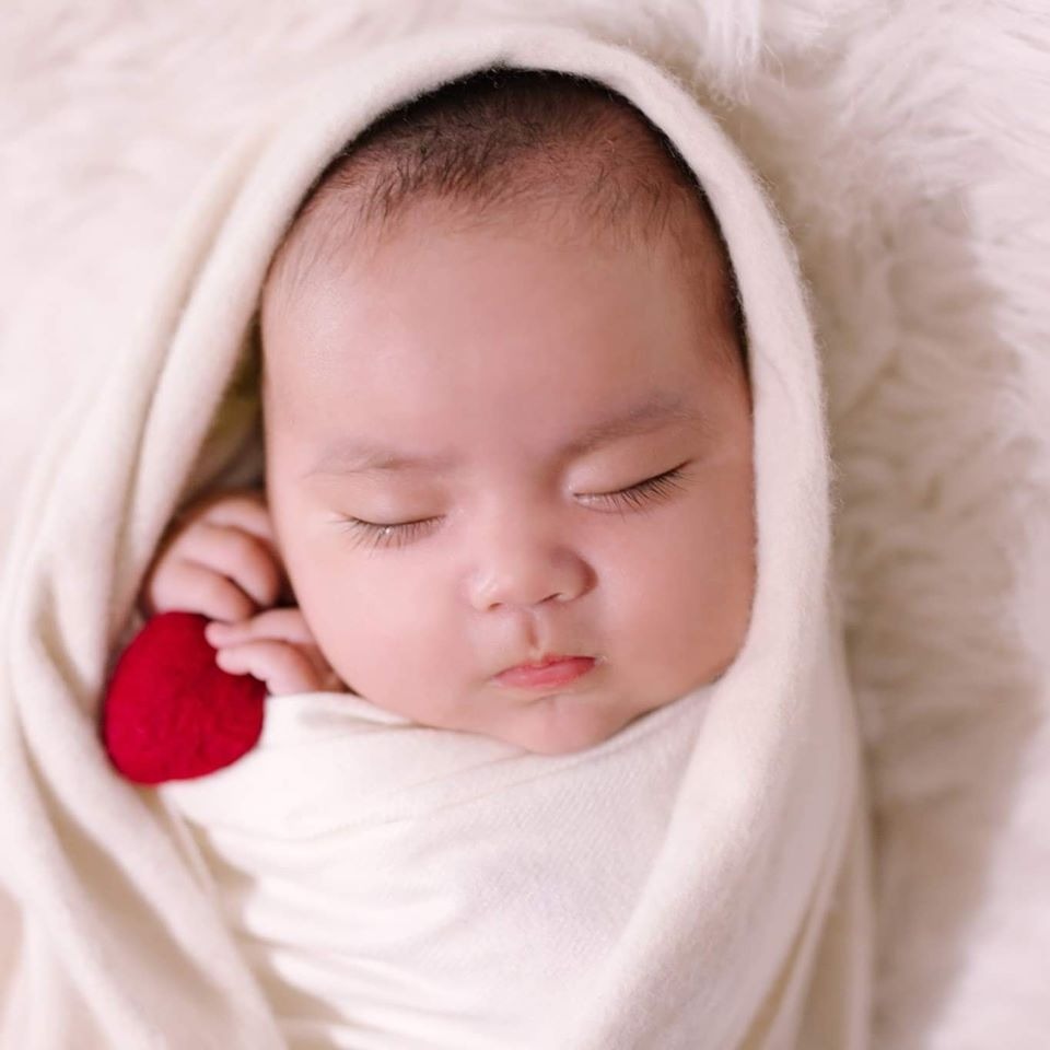 🧷MỘT SỐ SỰ THẬT VỀ EM BÉ SƠ SINH:
- Trẻ sơ sinh là 1 tờ giấy trắng , chỉ có nhu cầu ăn , mút mát , ngủ , đái , ị , không có nhu cầu rung lắc , hát ru à ơi hay bế rong . Tất cả đều do người lớn tự suy diễn và tập thành thói quen cho trẻ .
- Trẻ sơ sinh sinh ra sẽ có tuần trăng mật (2-4 tuần đầu) . Đúng như tên gọi trăng mật , trong thời gian này bé chỉ ăn và ngủ , hầu như k có thời gian thức , mẹ cứ nghĩ em ngoan lắm cho đến khi hết trăng mật . Nhiều bé sẽ hết trăng mật ở tuần thứ 3 hoặc thứ 4 , bị lẫn lộn ngày đêm (ngày ngủ li bì , đêm ngủ 15-20p dậy 1 lần) , sau đó sẽ gặp wonder week (tuần khủng hoảng , phát triển và hoàn thiện kĩ năng) ở tuần thứ 5 mà các bà hay bảo là ra tháng nó hư đấy :))
- Trẻ sơ sinh hoàn toàn có khả năng tự ngủ mà k cần bế rong trên tay hằng tiếng đồng hồ . Chỉ cần mẹ biết cách chọn đúng phương pháp phù hợp với bé .
- Trẻ trên 6kg có thể tự tích luỹ năng lượng để ngủ xuyên đêm mà không cần ăn . Giấc ngủ đêm dài rất quan trọng với phát triển trí não và chiều cao của trẻ , chứ chỉ ăn thôi thì chưa đủ . Nhu cầu ngủ đêm của trẻ sơ sinh là 11-12 tiếng . Tuỳ độ tuổi và số kilogram của con mà quyết định con có còn ăn đêm không mẹ nhé. Con dưới 6kg thì chưa nên cắt ti đêm mà mẹ hãy cân nhắc theo EASY để giấc đêm của con được tốt hơn .
- Trẻ sơ sinh có rất nhiều tiếng khóc : khóc đói , khóc cần mẹ vỗ về , khóc nóng/lạnh , khóc buồn ngủ , khóc bỉm bẩn , ... mỗi tiếng khóc đều có tone và cường độ khác nhau nên không phải cứ khóc là auto bú auto đói như truyền thuyết các bà để lại , chỉ cần bình tĩnh hoặc cho con theo 1 lịch sinh hoạt cố định là phân biệt đc rất dễ dàng .
- Lúc trẻ cần vỗ về trấn an chỉ cần mút mát , k cần bú . Đó là lí do sinh ra cái ti giả . Có 1 cái ti giả luôn thường trực trên cơ thể bé , chính là ngón tay . Chính vì thế đừng bgio cản bé mút tay .
- Ông bà k cho bế đứng , sợ trụn lưng trẻ , nhưng lại luôn mặc định cho trẻ nằm võng - thứ gây ảnh hưởng rất lớn đến cột sống của bé , kể cả có cái nôi tre hay lót khăn đều có hại . Thứ trẻ cần là 1 chiếc giường k rung lắc và 1 tấm nệm ép vừa đủ cứng để nằm .
- Trẻ dưới 6 tháng chỉ cần sữa mẹ/sữa công thức là đủ , tuyệt đối k cho trẻ uống thêm nước vì sẽ gây ngộ độc nước . Nếu pha sct k đúng tỉ lệ cũng sẽ gây ra hiện tượng này .
- Trẻ sinh ra sẽ có phản xạ moro và chưa tự làm chủ đc tay chân của mình nên thường bị giật mình và đập tay vào mặt , sau đó sẽ khóc . Quấn giúp trẻ có cảm giác đc ôm chặt và hạn chế đc việc giật mình đập tay vào mặt lúc ngủ nên quấn giúp trẻ ngủ đc sâu và ngon giấc hơn chứ k phải lấy gối hay bất cứ cái gì khác đè lên bụng trẻ để “chém trợ”. Phản xạ moro sẽ dần biến mất khi trẻ lớn , thường thì từ 3-4 tháng tuổi , nên 4 tháng là thời điểm thích hợp để cai các công cụ hỗ trợ như quấn , ti giả , white noise . Một số bé sẽ cai sớm hơn và 1 số bé sẽ có nhu cầu cai muộn hơn .
- Chu kỳ giấc ngủ của trẻ sơ sinh ngắn hơn so với người lớn , trẻ sơ sinh ngủ nhiều ở tình trạng chuyển động mắt nhanh (REM) - điều cần thiết cho sự phát triển đặc biệt của bộ não bé .
- Một giấc ngủ của trẻ sơ sinh kéo dài khoảng 50 phút . Một giấc ngủ dài bao gồm nhiều chu kì ngắn , mỗi chu kì được bắt đầu bằng giấc ngủ nông (ngủ và mơ cùng lúc) và tiếp tục đi vào giấc ngủ sâu . Vì thế trẻ thường thức dậy sau 45-50p đi ngủ , nếu k có sự can thiệp của ng lớn (bế ra khỏi môi trường ngủ vì tưởng trẻ đã thức) thì bé sẽ tự ngủ lại , một số bé phải khóc tự trấn an mới ngủ lại đc . Đây là lý do sinh ra nút chờ .
- Giấc ngủ nông thường trông giống như trẻ đang thức : trẻ có những cử động trên gương mặt , và cơ thể . Đó là dấu hiệu não của trẻ đang hoạt động, hệ thần kinh đang kết nối với nhau , trẻ đang học các biểu hiện và truyền đạt cảm xúc . Chúng ta có thể lầm tưởng rằng trẻ đang thức , nhưng hoàn toàn không phải , giấc ngủ này cần được tôn trọng tuyệt đối .
- Trẻ sẽ trải qua các thời kỳ khủng hoảng , phát triển và hoàn thiện kỹ năng , gọi là wonder weeks (ww) , mỗi mốc ww qua đi trẻ sẽ học đc nhiều cái mới mẻ hơn , nhưng trước đó là 1 khoảng thời gian biếng ăn sinh lý , cáu kỉnh , khó ngủ , đeo bám , mè nheo . Càng lớn bão ww sẽ càng mãnh liệt . Việc mẹ cần làm trong khoảng thời gian này là tôn trọng con , k ép con bú/ăn , và kiên nhẫn với con .
- Trẻ sinh ra đã có gen tóc mặc định , nên k phải cứ cắt tóc máu thì tóc sau sẽ tốt hơn . Cái tốt hơn mà ng lớn lầm tưởng ở đây chính là sự đồng đều khi mọc lại tóc nên ng lớn nghĩ sau khi cắt trông tóc có vẻ đen hơn và dày hơn . Sai lầm .
- Thân nhiệt của trẻ sơ sinh luôn cao hơn người lớn , vì thế nên khi ng lớn cảm thấy lạnh trẻ mới thấy mát . Nhiệt độ phòng lý tưởng để trẻ ngủ ngon là 22-24 độ . Lưu ý nhiệt độ phòng k phải là nhiệt độ hiển thị ở trên điều khiển điều hoà .
- Trẻ ốm là do vi rút , vi khuẩn , cái điều hoà không có tội nên đừng đổ lỗi do điều hoà . Nếu có lỗi do điều hoà thì chính là người lớn k chịu vệ sinh điều hoà .
- Em bé & thậm chí là ng lớn sẽ ngủ rất nhanh hoặc bình tĩnh hơn nếu có white noise (tiếng ồn trắng). Tuỳ vào sở thích của mỗi bé mà có bé thích tiếng mưa, có bé thích tiếng nhiễu tivi, có bé thích tiếng vỗ của biển hoặc tiếng nước chảy, tiếng máy sấy, tiếng tim đập, ...
- Trẻ bú xong cần đc ợ hơi thật kỹ . Hơi chính là nguyên nhân làm trẻ quấy khóc khi bú . Một số bé cần đc ợ hơi cả giữa bữa chứ k chỉ sau khi kết thúc bữa . Đưa ti trẻ vẫn bú nhưng nút đc vài cái lại ưỡn ng co chân khóc . Việc mẹ cần làm là dừng bú và ợ hơi cho bé , sau đó tiếp tục bữa ăn (vì sữa là thức ăn của trẻ sơ sinh nên có thể gọi bú = ăn)
- Trẻ thức chơi đêm vì ngày ngủ quá nhiều , waketime chưa đủ . Điều này k có nghĩa là ngày bắt trẻ thức thật nhiều thì đêm trẻ sẽ ngủ xuyên đêm . Ở mỗi độ tuổi bé sẽ có khả năng thức khác nhau. Càng lớn khả năng thức càng dài. Nhưng k phải vì thế mà mẹ cho bé thức bnhieu cũng đc. Bé sơ sinh k thể theo lịch sinh hoạt của ng lớn. Nếu mẹ nghĩ ngày con thức càng dài để đêm con ngủ tốt hơn thì mẹ đã sai hoàn toàn và chỉ làm con bị overtired, càng khó ngủ & trằn trọc nhiều hơn thôi. Để con ngủ tốt ban đêm thì ban ngày con cần những giấc nghỉ ngơi ngắn k quá 2.5 tiếng/lần phân bố xem kẽ với khả năng thức của con. Để giúp con có lịch sinh hoạt phù hợp nhất mà k làm con quá sức thì mẹ nên tìm hiểu về EASY.
- K phải cứ cho trẻ đi ngủ càng muộn thì đêm trẻ sẽ k dậy . Nếu cho bé đi ngủ quá muộn so với nhu cầu của bé (vdu 7h tối con cần đi ngủ , nhưng ng lớn nghĩ ngủ giờ này thì đêm dậy quấy nên bắt con thức đến 9-10h đêm mới cho đi ngủ) sẽ làm con overtired , gắt ngủ và khó vào giấc hơn .
- Đầu là chỗ thoát nhiệt của con nên trẻ k cần đội mũ khi nhiệt độ >20*, cũng k cần ủ kín mít vì chỉ làm con đổ mồ hôi nhiều hơn, nhất là trong thời tiết nắng nóng ntn.
- Rụng tóc vành khăn, vặn mình, trớ,... đều là hiện tượng sinh lý của trẻ. Càng lớn hiện tượng vặn mình sẽ càng giảm. Còn rụng tóc vành khăn là do chỗ tiếp xúc với đầu lúc con nằm. Nếu mẹ không yên tâm hãy đưa con đi khám để biết con rụng tóc bành khăn là do sinh lý hay thiếu chất. Mẹ chỉ đc bổ sung duy nhất vitamin D cho con. Tuyệt đối k tự ý bổ sung calcium nếu k có đơn thuốc của bác sĩ hay mẫu xét nghiệm.
Nguồn: Sưu Tầm