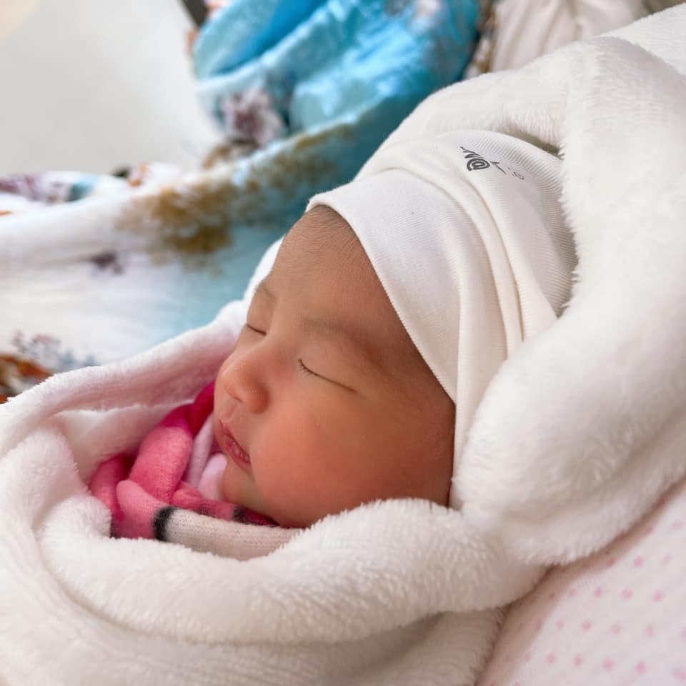 Một hành trình đi đẻ đầy gian nan các mẹ ạ! 
Chiều 30 Tết e đau bụng, ra huyết hồng. Đi sâ thì bác sĩ bảo nhập viện để sinh.
Đêm giao thừa, các mẹ nhập viện sau thì lần lượt lên bàn đẻ, còn hai vợ chồng e thì cứ ngồi nhìn, chờ đợi 1 cơn đau đẻ 😂. 
Đến sáng m1, bác sĩ khám trong mà tử cung chưa có dấu hiệu mở nên cho xuất viện về đi chơi Tết.  
Đến chiều m6 Tết cơn đau dày dần, đi sâ bác sĩ bảo phồng ối rồi nhập viện để đẻ ngay. 
E nhập viện lúc 9h tối, tử cung mở 2p, vỡ ối nhưng không có cơn rặn, hộ lý tiêm thuốc kích sinh,, và sau đó thì cơn đau dồn dập, bác sĩ thì bảo đến khi nào có cơn rặn thì gọi,hộ lý thì bắt nằm 1 chỗ , 1 mình em nằm lạnh lẽo trên bàn đẻ không ai trực, không cho người nhà vào. Em nằm chịu đựng từng cơn đau  đến 12h đêm, không chịu nổi nữa e khóc; chồng, mẹ và chị gái sốt ruột quá chạy vào với e rồi chạy đi tìm bác sĩ, tìm mãi mới thấy cô hộ lý, vừa vào hộ lý vừa quát mắng rồi bảo “đẻ ai chẳng đau mà cứ kêu”, khám trong thì tử cung chỉ mở dc 3p, rồi bà í bảo đến sáng mới đẻ trong khi đã tiêm thuốc kích sinh và e đã vỡ ối từ trước 🥲
E nghiến răng chịu đựng đến gần 2h sáng thì kiệt sức, nôn trên bàn đẻ, người ướt đẫm mồ hôi,lúc đó e xin mổ chủ động, hộ lý bảo e không chịu khó và còn nói “bên đạo mà cũng đòi mổ à” 😩. (Gđ e theo đạo công giáo )
Chồng e chạy đi kêu bác sĩ, bs vào khám xong bảo làm thủ tục mổ lấy thai ngay lập tức nếu không sẽ vỡ tử cung.
2h sáng e được đưa vào phòng mổ, các thủ tục gây tê abc xong xuôi thì em nghe tiếng khóc chào đời của con gái, lúc đó chực trào nước mắt, bác sĩ cắt rốn vệ sinh cho con xong đưa đi luôn chứ e không được da kề da với con. Đến 3h thì e được đưa về phòng hồi sức cấp cứu.
Lúc đưa bé ra, bác sĩ bảo với mẹ em rằng đưa bé ra hơi muộn, nhưng mẹ tròn con vuông rồi nên người nhà đừng lo lắng 😟 
Con e chào đời lúc 2h16’ ngày 19-2-2021; nặng 2,8kg 
Tvia bé ngoan lắm các mẹ ạ 🥰