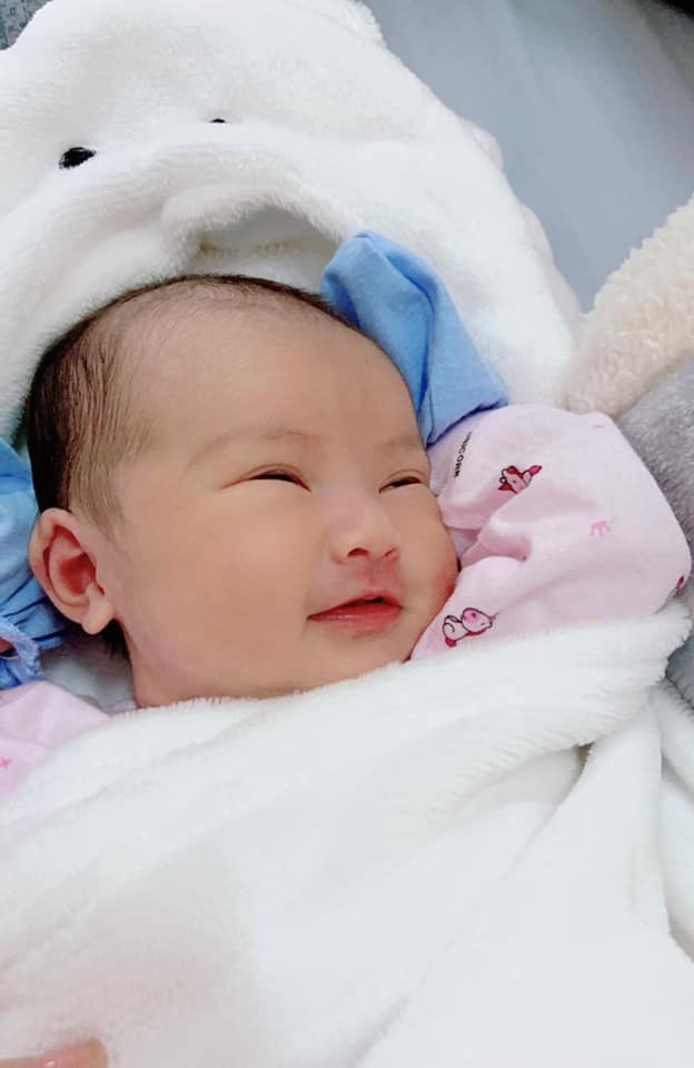 Một hành trình đi đẻ đầy gian nan các mẹ ạ! 
Chiều 30 Tết e đau bụng, ra huyết hồng. Đi sâ thì bác sĩ bảo nhập viện để sinh.
Đêm giao thừa, các mẹ nhập viện sau thì lần lượt lên bàn đẻ, còn hai vợ chồng e thì cứ ngồi nhìn, chờ đợi 1 cơn đau đẻ 😂. 
Đến sáng m1, bác sĩ khám trong mà tử cung chưa có dấu hiệu mở nên cho xuất viện về đi chơi Tết.  
Đến chiều m6 Tết cơn đau dày dần, đi sâ bác sĩ bảo phồng ối rồi nhập viện để đẻ ngay. 
E nhập viện lúc 9h tối, tử cung mở 2p, vỡ ối nhưng không có cơn rặn, hộ lý tiêm thuốc kích sinh,, và sau đó thì cơn đau dồn dập, bác sĩ thì bảo đến khi nào có cơn rặn thì gọi,hộ lý thì bắt nằm 1 chỗ , 1 mình em nằm lạnh lẽo trên bàn đẻ không ai trực, không cho người nhà vào. Em nằm chịu đựng từng cơn đau  đến 12h đêm, không chịu nổi nữa e khóc; chồng, mẹ và chị gái sốt ruột quá chạy vào với e rồi chạy đi tìm bác sĩ, tìm mãi mới thấy cô hộ lý, vừa vào hộ lý vừa quát mắng rồi bảo “đẻ ai chẳng đau mà cứ kêu”, khám trong thì tử cung chỉ mở dc 3p, rồi bà í bảo đến sáng mới đẻ trong khi đã tiêm thuốc kích sinh và e đã vỡ ối từ trước 🥲
E nghiến răng chịu đựng đến gần 2h sáng thì kiệt sức, nôn trên bàn đẻ, người ướt đẫm mồ hôi,lúc đó e xin mổ chủ động, hộ lý bảo e không chịu khó và còn nói “bên đạo mà cũng đòi mổ à” 😩. (Gđ e theo đạo công giáo )
Chồng e chạy đi kêu bác sĩ, bs vào khám xong bảo làm thủ tục mổ lấy thai ngay lập tức nếu không sẽ vỡ tử cung.
2h sáng e được đưa vào phòng mổ, các thủ tục gây tê abc xong xuôi thì em nghe tiếng khóc chào đời của con gái, lúc đó chực trào nước mắt, bác sĩ cắt rốn vệ sinh cho con xong đưa đi luôn chứ e không được da kề da với con. Đến 3h thì e được đưa về phòng hồi sức cấp cứu.
Lúc đưa bé ra, bác sĩ bảo với mẹ em rằng đưa bé ra hơi muộn, nhưng mẹ tròn con vuông rồi nên người nhà đừng lo lắng 😟 
Con e chào đời lúc 2h16’ ngày 19-2-2021; nặng 2,8kg 
Tvia bé ngoan lắm các mẹ ạ 🥰