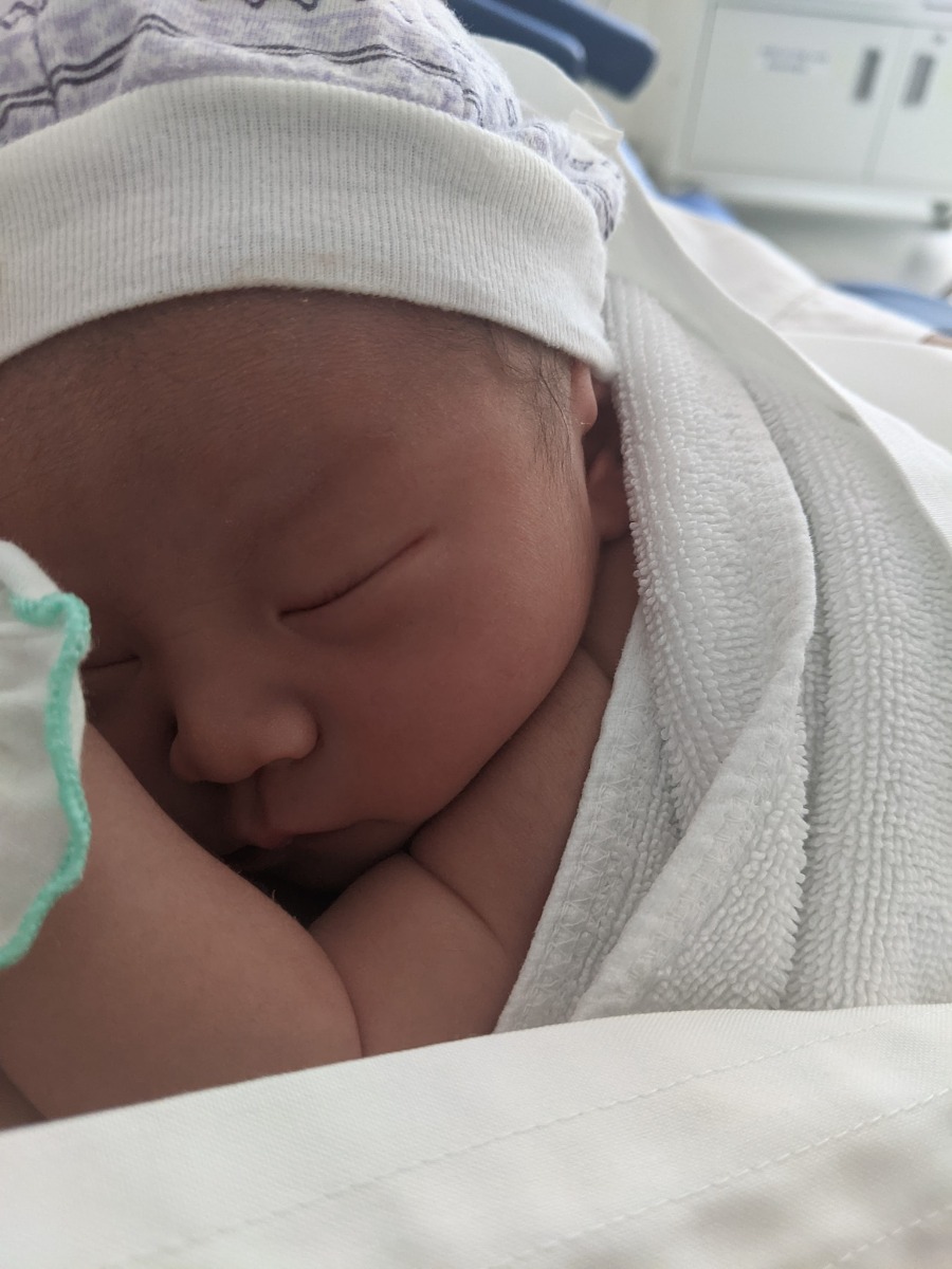 NHẬT KÝ VƯỢT CẠN TẠI BV VIỆT PHÁP HN - CẢM XÚC HÌNH SIN

Vợ mình bắt đầu có dấu hiệu chuyển dạ lúc 11h30p đêm ngày 10/04. Cơn chuyển dạ đến tư từ, không quá dồn dập nhưng mỗi lúc một tăng lên cả về cường độ lẫn chu kỳ. Vợ mình khá là kém khoản chịu đau nhưng lần này thật bất ngờ khi vẫn nhắm mắt nằm đến khi trời sáng khi tự mình vượt qua trên dưới 10 cơn đau chuyển dạ với cường độ mỗi lúc một tăng.

Sáng 11/04, lúc 5h00 phút. Vợ mình nhận chỉ định nhập viện do CTC đã mở được 1cm đầu tiên. Lúc này tâm trạng khá hồi hộp và vui mừng. Mình tất tưởi chạy đi làm thủ tục nhập viện và đặt phòng Single + Visitor cho 1 đêm sinh thường tại HFH. Trong lúc đó vợ mình được di chuyển lên phòng chờ và gắn máy Monitor theo dõi liên tục. 7h35p vợ mình vỡ ối, mình và vợ đều sẵn sàng cho cuộc vượt cạn. Trước khi làm giảm đau, gây tê ngoài màng cứng, thực sự là quãng thời gian khó khăn nhất khi những cơn đau đến ngày một dồn dập, vợ mình bị cơn đau chế ngự hoàn toàn.

11h00 vợ mình hoàn thành gây tê ngoài màng cứng, và di chuyển lên phòng đẻ số 3. Lúc này CTC đã mở được 4 cm. Tâm trạng cả 2 vợ chồng đều rất vui vì mọi thứ đều theo lộ trình ước tính trước đó. Cho đến khi Bác sỹ khám khi CTC đã mở đc 9 cm, Bác sỹ mặt co lại, xám xịt và thông báo với mình 1 tin, khiến mình và vợ mình mất hoàn toàn bình tĩnh. Nguyên văn "Em bé ngửa mặt lên đồng thời, monitor đã hoàn toàn không bắt được tim thai trong 10p" mình đứng ngay sát vợ lắng nghe từng câu chữ, mắt thì nhìn máy monitor chỉ 1 dấu ? vàng ệch trên màn hình monitor. Sau 1p suy nghĩ, bác sỹ và mình đều đưa ra quyết định. Mổ đẻ khẩn cấp. Sau khi nghe tin, người vợ mình run lên liên hồi, phần do lạnh, phần do lo sợ. Lo sợ cho sự an nguy của con gái mình.

Sau khi ký tá mọi giấy tờ và ký vào bản cam kết phẫu thuât với lý do Thai ngửa, Suy thai. Yêu cầu mổ gấp. Mình quay lại với vợ, chỉ kịp hôn lên trán vợ và nói "2 mẹ con cố lên, bố biết 2 mẹ con sẽ làm được" rồi đứng như trời trồng khi nhìn xe đẩy, đẩy chiếc giường vào phòng mổ trong khi các bác sỹ vẫn liên tục truyền các lọ thuốc vào tay vợ mình.
Lúc đấy, cổ họng mình nghẹn lại. Nhưng vẫn nhanh chóng chạy thẳng xuống Khoa Sản, nhận quần áo sạch, tắm và sát trùng cơ thể để tiến hành Da kề da với con gái. 1 phút rồi 5 phút rồi 10 phút, thời gian mình đếm đến từng tíc tắc. Chỉ một mình mình với cái hành lang màu hồng. Lần đầu tiên mình chảy nc mắt vì sợ hãi và cô độc.

13h35p. Chị chăm sóc kéo theo 1 xe lồng. Mình chạy đến hỏi chị. Chị ơi, em bé của bạn Phạm Thùy Trang đúng không chị? Chị nói "Đúng rồi! Em ra ngoài lúc 13h28p, em gái và em nặng 2.5kg. Sức khoẻ của em và mẹ đều tốt. Anh nằm xuống để mình Da kề da với em nhé". Mình đỡ con vào lòng, hỏi liên tục chị chăm sóc về thông tin của vợ. Chị trấn an mình bằng thông tin rằng vợ mình vẫn tỉnh táo, các bác sỹ đang tiến hành phần còn lại của ca phẫu thuật. Vừa da kề da với con mà nước mắt ngấn lên. Phần vì hạnh phúc, phần vì lo cho vợ.

16h55p. Vợ mình đc trả về phòng. Mình cùng con đi về với vợ. Cho đến khi mình gặp được vợ, thấy vợ tỉnh táo tươi cười. Lúc đó cơ hàm, cơ mặt, cơ tay mới thực sự đc thả lỏng. Mình trả con cho vợ và tự nhủ. Thành công rồi, mình làm bố rồi!!!

Một trải nghiệm đưa vợ đi đẻ mà có lẽ mình sẽ không thể nào quên được. Từng cung bậc cảm xúc mình từ vui mừng đến kinh hãi, lo lắng cho đến hạnh phúc khi nhìn vợ con bình an trở về.

P/s: Cháu chào các cô các chú. Cháu tên là Tuệ Minh, tên ở nhà là Tô. Cháu nặng 2.5 kg và thích được xoa lưng đi ngủ ạ. Các cô, các chú ủn mông cho cháu hay ăn chóng lớn nha. 🥳🥰👶

P/s 2: Chân thành cảm ơn Bác sỹ Nghị cùng kíp trực đã đỡ đẻ cho vợ em. Với sự chân thành, cẩn thận và tâm huyết hết mực. Cảc ơn Bác sỹ Quyết và Bác sỹ Thu đã tận tình thăm khám trong suốt thai kỳ. Em chắc chắn sẽ chọn HFH tại tập 2. Các mẹ yên tâm khi lựa chọn HFH nhaa.