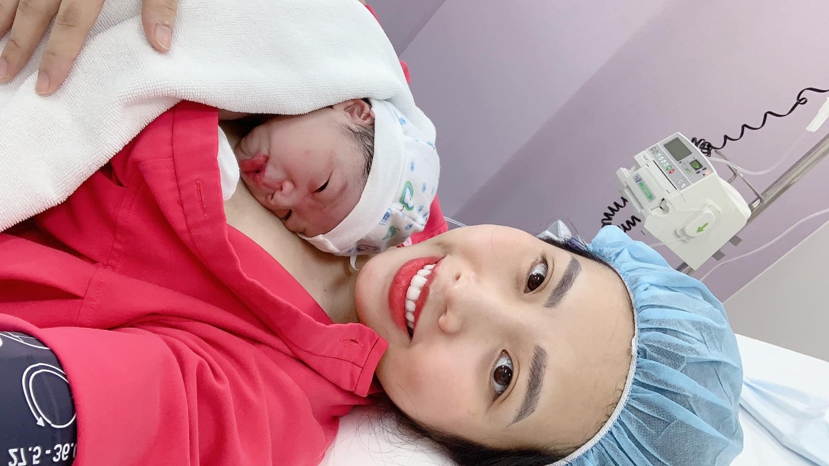 Review sinh tại Việt Pháp

Chào các mẹ, mình đã sinh được gần một tuần. Nay mình đã vượt cạn thành công, viết một chút review cho các mẹ sắp sinh mùa dịch giống mình.

Lần 1 đẻ ở Vinmec Times City nằm chờ sinh + đau hơn 14 tiếng vật vã mới đẻ xong. Lần 2 đúng là con dạ, siêu nhanh chóng và nhẹ nhàng. 10h kém vào viện với bà ngoại, khai báo y tế online trước cho nhanh nhưng mà lúc bước qua cổng bà ngoại vẫn không được vào, đội ngũ y tế nói nếu mình có chỉ định nhập viện sinh bà mới được vào cùng, lúc ý đang đau rồi mà vẫn phải đi 1 mình vào lối cổng cấp cứu, sáng chủ nhật nên viện vắng, vào khoa cấp cứu báo em đau bụng sắp sinh rồi, yêu cầu đẩy xe lăn lên khoa sản đi thì được đưa lên tầng 4. Vẫn là khu khám quen thuộc mà hôm nay vắng quá, vào phòng đo monitor, chị hộ sinh khám trong xong cho nhập viện luôn. Mình có hỏi quy định đi sinh mùa dịch thì được trả lời là, nếu người nhà có nguyện vọng ở lại chăm thì làm xét nghiệm covid và đóng thêm 1300k tiền phí người nhà ở lại, tiền up phòng sẽ được free (không mất thêm 2tr như bình thường), tuy nhiên ở viện không làm xét nghiệm nên mình có tìm 1 số chỗ xét nghiệm, nhọ cái đúng lúc dịch căng thẳng nên medlatec báo sau 2 ngày mới có kết quả, và không phải ai người ta cũng xét nghiệm cho. Thôi xác định không có người nhà ở lại chăm vậy 😭😭😭.

Cơn gò dồn dập đau khủng khiếp, giục chị hộ sinh cho người nhà em lên đi chị, nhưng chị bảo đo monitor xong, em nhận phòng tắm rồi đợi lên phòng đẻ gây tê ngoài màng cứng xong người nhà sẽ được lên nhé. Huhu thế hoá ra lúc đau đẻ một mình là có thật. Nhưng vì đây là tập 2 rồi cộng với việc chị hộ sinh đón mình lúc rất nhiệt tình, thân thiện hỏi han nên cũng được an ủi phần nào.

Bác sỹ gây mê cho mình hình như tên là Hà =.=. Mình kể với bác sỹ là lần trước em gây tê vẫn bị buốt lưng từng cơn không khác gì đau đẻ. Chị bảo uh để c xem, cột sống của mình lại còn hơi vẹo, chọc mãi mới cho thuốc vào được, chị xử lý cả vùng lưng nên mình không bị đau vật vã như lần trước. Lúc làm giảm đau là mình đang đau lắm rồi vì mở nhanh, bác sỹ vừa làm vừa dỗ dành. Và cuối cùng nhờ có chị mà em đẻ xong vẫn có sức selfie 1001  bức ảnh tươi tắn :))

Hôm mình sinh là bác Yến trực, mọi người cứ bảo bác lạnh lùng nhưng mà mình thấy bác chỉ hơi ít nói chút thôi, tập trung chuyên môn đỡ đẻ nhanh gọn và khâu cho mình cẩn thận. 

Điều ấn tượng sau khi sinh xong ở VF đối với mình đó là đội ngũ nữ hộ sinh cực kỳ chuyên nghiệp, tận tình. Mùa dịch nên sau khi sinh xong người nhà phải về luôn nhưng các nữ hộ sinh luôn chủ động take care. Ban đầu khi đăng ký VF mình cũng hơi băn khoăn, xác định sẽ up phòng và thêm phí cho người nhà ở lại chăm nhưng rồi dịch tới không cản được :))  Sau khi trải nghiệm thực tế thì đúng là sinh thường ở VF không cần người nhà chăm (sinh mổ thì mẹ cháu chưa trải qua nên không biết). Sản phụ có thời gian yên tĩnh, nghỉ ngơi, tối mình gửi em bé cho các cô và lúc nào con muốn ăn thì các cô lại bế vào cho ti mẹ, hôm mình sinh mọi vấn đề đều được hỗ trợ tận tình, cô nào cũng xinh đẹp, tươi tắn ban ngày cũng như ban đêm nên mình khá hài lòng. Tối sợ con hạ đường huyết (lúc chiều bé đo đường huyết hơi thấp) mình nhờ các cô pha sữa thì các cô động viên bảo mẹ có sữa mà và hướng dẫn cho bé ti mẹ.

Mình còn ấn tượng với cô Kiều Lan - hộ sinh trưởng, mấy lần đi khám thấy cô đi qua đi lại thấy mẹ bầu vắt chéo chân là cô cười nhắc đừng ngồi như thế không tốt cho e bé. Có một lần đi khám được cô mắc monitor và gặp cô đi khám buồng sau sinh cùng bác sỹ. Vì cô lúc nào cũng tươi tắn hỏi han nên cảm thấy được cưng chiều lắm ấy. Cô còn trêu lần sau đẻ vẫn chọn VF chứ hehe. 

Các mom cứ tự tin đi sinh mùa dịch nhé ^^