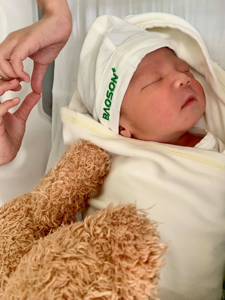 CẢM THẤY BIỂT ƠN! 🙏🏻

Xin chào các mẹ bầu và các mẹ bỉm đã từng sinh và đang thăm khám cũng như tham khảo lựa chọn Bảo Sơn là nơi chào đón đứa con bé bỏng của mình.

- Mình mới sinh hôm 21/06, giờ cơ thể cũng đang dần đi vào quỹ đạo nên mình ngồi viết review cho các mẹ đây. Hơi dài nhé các mẹ.

- Tập 1 năm 2014 mình sinh thường, quan niệm khi đó tới nay vẫn k thay đổi đó là đẻ sẽ rất mệt nên cần lựa chọn bệnh viện bác sĩ tốt là 1, dịch vụ tốt là 2. Khi đó mình đang ở Saigon nên mình lựa chọn Bvqt Hạnh Phúc. Mọi thứ k thể chê vào đâu đc cũng như thời kỳ bầu và sinh bé thứ 1 rất dễ dàng và nhẹ nhàng.

- Tới tập 2 lần này, trong đầu mình vẫn luôn đinh ninh là mình sẽ sinh thường. Khi cấn bầu, mình đã tham khảo các bv từ Vinmec, TC, HN,… nhưng đi sẽ hơi xa với nhà mình, mà mọi người hay bảo đứa thứ 2 sinh sẽ nhanh hơn đứa thứ 1. Nên khi đó mình tham khảo Bảo Sơn vì gần nhà nhất. Khách quan thực sự thì cơ sở vật chất tại Bảo Sơn chưa đc đầu tư mạnh so với những bệnh viện trên nhưng vẫn đủ tiêu chí sạch sẽ, riêng tư. Mà nhất là khi mình check ra thì trc đó các bác sĩ tại BS toàn là trưởng-phó khoa tại các bệnh viện phụ sản. Nên mình quyết định mua gói sinh thường tại BS từ 22w. Bây giờ mình mới thấy đây là lựa chọn sáng suốt của cuộc đời mình.

- Trong các thời kỳ thăm khám thì cũng như nhiều mẹ review, siêu âm bác sĩ nói kỹ càng về các chi tiết của em bé (mặc dù nhiều lúc mình vẫn k hình dung ra 😅😅), suất ăn khi khám xong ở bên khách sạn BS thì mình luôn ăn súp bí đỏ vì mình thấy rất ngon và vừa miệng mình. Thường thì mình sẽ đi khám vào buổi chiều vì vắng hơn, trừ đợt xét nghiệm đường huyết lúc 28w và lấy máu tuần 36 là mình đi khám vào buổi sáng. 

- Tuần thứ 36 mình xn huyết học thì bác sĩ có nói mình bị tiểu cầu thấp và chỉ định mình qua bên viện Huyết học để xét nghiệm kỹ lại về tiểu cầu, nếu quá thấp mà k biến chuyển thì khi sinh mình sẽ phải truyền tiểu cầu. Và cứ cách 10d mình lại lấy máu bên viện HH 1 lần để kiểm tra (tổng 2 lần). Tới khi 38w5d (19/06) tới lịch mình tái khám, bác sĩ check thấy tiểu cầu mình đã tăng hơn và siêu âm vẫn bình thường nên bác sĩ dặn tới 25/06 bên viện HH hẹn mình qua lấy máu thì vẫn qua để chắc chắn 1 lần nữa cho yên tâm vì dự sinh mình 28/06.

- 1:22am ngày 21/06 mình đang ngủ tự nhiên oá nước ra mình tưởng tè dầm, mắt nhắm mắt mở vào nhà vệ sinh để đi vs thì nhìn thấy quần chíp be bét máu, ngó xuống nước tiểu cũng đầy máu như khi còn kinh nguyệt. Hoảng quá gọi mẹ để chuẩn bị vào viện. Thay quần áo rồi thay đồ, lên xe là 1:44am, tới bệnh viện là 1:54am. Đi đến cửa có anh bảo test Covid đã mình bảo “để sau đi em vỡ ối rồi” (rất may trên đường đi không bị oá nước hay gì cả và mình vẫn nghĩ vỡ ối). 

- Lên trên tầng 5 thì chị y tá đưa vào phòng và mình thấy mót đi vệ sinh, mà cũng lại ra máu như ở nhà, chị y tá gọi bác Cốc ra khám trong cho mình thì nước máu lại ào ra, bác Cốc bảo theo dõi thêm 1 lúc. 3p sau bác Cốc lại khám trong cho mình thì máu ào ra như cắt tiết tong tỏng dưới sàn. Mình kịp nghe thấy bác Cốc bảo: “Thôi k đc rồi gọi ekip mổ gấp”. Tới khi đó mình sợ gồng hết cả người lên nhưng cũng chỉ tâm lý là sắp phải mổ, chứ chưa biết chuyện nguy hiểm ntn. 

- Mình được đẩy lên tầng 7, mọi thứ diễn ra nhanh chóng từ tiêm tê vào tuỷ sống, sau đó tấm vải che ngang mình k nhìn thấy bên dưới diễn ra ntn nữa. Phần thân dưới mình tê liệt hoàn toàn, mình bị buồn nôn, buồn ngủ lắm và mình hỏi mình có thể ngủ đc k, bác sĩ gây tê cho mình bảo “em bé chuẩn bị ra rồi, giờ bác sĩ giằng xé bụng mình ntn cũng kệ nhé”. Và đúng là cảm giác bị giằng xé bụng thật sự, k có cảm giác đau nhưng cảm giác bụng mình bị giằng co cho tới khi nghe thấy tiếng em bé khóc. Thực sự là mình cũng k biết dao rạch bụng mình lúc nào 😅🙄

- Mình có hỏi bác sĩ gây tê cho mình là em bé có ok k, khi biết con ổn rồi mình muốn ngủ, mặc kệ bên dưới đc khâu vá ntn. Lúc y tá mặc đồ cho em bé xong và áp má em và má mình, cảm giác mình có cả bầu trời trong tay.

- Rồi mình được nằm truyền và có y tá ngồi theo dõi mình, cho tới khi 2 chân mình co lên đc thì đưa mình về phòng sau sinh. 

- Thời gian kể từ khi ở nhà có dấu hiệu đến lúc em bé ra đời chỉ vỏn vẹn trong vòng 1 tiếng, nhanh hơn vũ bão.

- Mình ở phòng 503 và up to 4 ngày phòng riêng nên người nhà cũng có suất ăn. Vì chồng mình đang ở nước ngoài nên bé lớn 7t của mình cũng vào viện vì ở nhà k ai trông (mẹ mình ở viện chăm sóc mình). Nchung người nhà chẳng phải làm gì cả, bé nhà mình ăn cơm viện ngon lành vì đồ ăn đầy đặn mà ngon miệng, sáng nào cũng chọn ăn phở 😂

- Sau sinh 2 hôm bác sĩ mới nói cho mình biết là mình bị bong rau non, máu ra như cắt tiết, chẳng có cơn gò hay tử cung mở gì cả thì chẳng thể sinh thường đc, chỉ cần chậm 1 chút thôi là phải cắt bỏ tử cung và hỏng em bé 😭😭. Ôi nghĩ tới việc 1 đứa bé đã 39w mà còn k đc làm người chắc mình điên dại mất, cắt bỏ tử cung chẳng có nghĩa lý gì cả. 

- 4 ngày 3 đêm ở viện mình thường xuyên đc các bác sĩ qua hỏi han và các y tá ở đây tận tình chăm sóc, giúp thay bỉm và pha sữa cho em bé ăn. Đến khi mình về bạn y tá Thương còn xách đồ cho mấy mẹ con bà cháu mình lên xe. Mình thì ăn đủ combo đau từ vết mổ, co dạ con, ngực căng nhức. Nếu phải tự làm mọi việc nữa thì chắc ngất 😅😅. 

- Vậy mới thấy sự lựa chọn của mình là sáng suốt, cả đời này biết ơn bác Cốc và ekip mổ cho mình ngày hôm đó, nếu k thì k biết 2 mẹ con mình đang như thế nào. Lựa chọn đẻ dịch vụ thì thích thật nhưng điều quan trọng tiên quyết là bác sĩ chuyên môn tốt hay không. Mà bv BS đang nâng cấp, mấy hôm mình ở viện là hơi ồn do sửa chữa nhưng em bé trộm vía ăn rồi ngủ, còn mình mệt nên cũng ngủ. Hai mẹ con bình an là đc, ồn ào chỉ như gió thoảng qua tai.

- Kính chúc bác Cốc và các y bác sĩ tại bệnh viện BS thật nhiều sức khoẻ để đỡ đẻ cho các mẹ bầu. Chúc bệnh viện đc nhiều mẹ bầu biết tới hơn để lựa chọn là nơi hạ cánh an toàn cho mẹ và bé. 

With Love ♥️