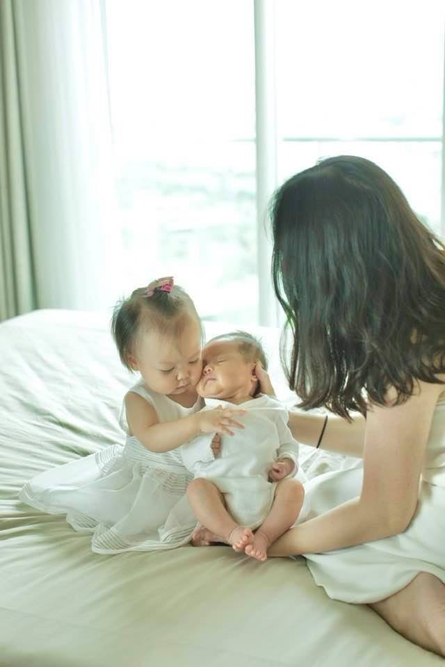 ❓ EM BÉ TRONG GIAI ĐOẠN 9-15 THÁNG CÓ THỂ NÀO “HƯ” KHÔNG?

Giai đoạn 9-15 tháng, con thường bắt đầu phát triển những hành động làm cho cha mẹ bối rối và bất ngờ. Mình hay nhận được tin nhắn của các mẹ nói là: “Con em, 10-11-12 tháng, bắt đầu hư rồi chị ạ! Ghê gớm lắm…”

Không, các mẹ ơi, hư là hư thế nào được? Tầm này tự nhiên mà sinh hư được à? Không có đâu!!! (Chú thích, một em bé sơ sinh khi chào đời chắc chắn có những đặc điểm tính khí riêng biệt. Có em bé dễ tính, có thể có em bé khó tính, nhưng chắc chắn trong các đặc điểm tính khí không phân ra “hư” vs. “ngoan”.)

Bố mẹ có biết, trong 1,5 năm đầu đời, em bé của chúng ta thay đổi và phát triển với một tốc độ vô cùng “vũ bão”? Từ giai đoạn nằm ngửa, đến khi con biết lật, biết ngồi, biết bò, trườn, và đi… đó là những kỹ năng vượt bậc, vài tháng lại thay đổi một lần, khiến cho sự nhận thức và liên hệ của trẻ về thế giới xung quanh liên tục biến chuyển và tiến hóa không ngừng.

Mới ngày hôm trước, khi con chỉ nằm ngửa, con nhìn mọi thứ hầu như ở phương nằm ngang, con nhìn thấy nhiều nhất có lẽ là cái … nọng cằm và cái lỗ mũi của mẹ 🙂 bỗng dưng đến một ngày con lật lẫy thuần thục, rồi ngồi lên vững chãi, con nhìn được xa hơn và rõ hơn, thì con sẽ thấy được “Ô, cái thế giới này có nhiều thứ quá vậy ta? Cái xa xa đen đen to to trên kệ phát ra âm thanh hình ảnh nhảy múa kia là cái gì? Cái trên nóc tủ kia là cái gì? Cái ở cạnh chỗ mình nằm là cái gì?” vv.. Giai đoạn 6 tháng đầu, người lớn bế con đi đến đâu, thì trải nghiệm của con mở ra đến đấy.

Trong khoảng 6 tháng đầu đời, hầu như các em bé sơ sinh không gây ra nhiều rắc rối cho người lớn, vì con vẫn chỉ “yên vị” ở một chỗ, chưa có khả năng di chuyển, nên người lớn có thể “kiểm soát” giới hạn của con khá tốt. Bắt đầu đến giai đoạn sau, khi con có thể tự di chuyển bằng cách bò, trườn, dò dẫm, và đi vững chãi… thì bố mẹ ạ, lúc này chúng ta không thể hoàn toàn kiểm soát được con nữa rồi.

Khi con bỗng nhận ra rằng: “À ha, mình không còn phải phụ thuộc vào ông / bà / bố / mẹ để di chuyển nữa. Bây giờ, mình hoàn toàn có thể tự “lê” thân đến bất cứ chỗ nào mình muốn rồi , ờ mây zing gút chóp mình ơi” 🙂. Thế là bố mẹ có biết, cả cái thế giới này, bỗng chốc trở thành một phòng thí nghiệm khổng lồ, một khu rừng thám hiểm thần tiên của con. Cái gì con cũng muốn sờ, muốn mó, muốn nắm, muốn cho cả vào miệng. Tại vì, cái gì cũng hấp dẫn với con hết.

Tất cả mọi thứ, ĐỀU LÀ MỚI MẺ. Từ cây tăm, con kiến, tới cái bình hoa, cái chung nước cúng bàn thờ ông địa… con sẽ muốn học hỏi và khám phá không từ món gì.

Kế đến, khi con vô tình làm được vài việc như đẩy, ném, đập, quăng… mà chính con còn chưa biết vì sao khi mình làm như thế này thì quả bóng, món đồ nó lại di chuyển như thế kia, và con cứ muốn lặp đi lặp lại động tác đó để thử nghiệm… thì vô tình con lại nhận được những phản hồi khó hiểu từ người lớn.

Việc con ném một quả bóng khi ngồi trong thảm chơi, thay ném miếng rau củ khi ngồi trên ghế ăn, ban đầu với con đó là một động tác ném. Việc con đổ hộp đồ chơi ra sàn nhà, hay đổ đồ ăn ra bàn, thì đó cũng là một động tác đổ. Nếu con chỉ đang bắt đầu thử một kỹ năng sử dụng đôi tay, thì có phải là con “hư” không ạ?

Nếu con nhận được sự phản hồi không nhất quán cho cùng một hành động: có lúc con được rất nhiều sự hô hào, cổ vũ, hoặc hùa vào cuộc vui; có lúc thì lại bị kết tội “hư đốn”, thậm chí bị la mắng, đánh vào tay hoặc bắt phạt… thì quả là khó hiểu cho một em bé dưới 1 tuổi: “Vì sao khi mình làm cùng một việc, có khi người lớn rất vui vẻ và khi khác lại rất cáu giận?”

Người lớn có thể vô tình nhìn nhận sai “mục đích” của trẻ, từ đó có cách phản hồi không phù hợp. Dần dà, trẻ lại tự “học” và “đúc kết” được rằng: “À, mỗi lần muốn làm cho người lớn thay đổi thái độ với mình, muốn người lớn xông vào đôi co, hay lăng xăng chú ý đến mình nhiều hơn, thì mình nên lặp đi lặp lại hành động này.”

Những em bé của chúng ta lớn nhanh lắm, thay đổi liên tục không ngừng, cứ mỗi khi người lớn nghĩ rằng: “À, mình nắm thóp được “nó” rồi, chiêu này mình có cách xử lý rồi” là y như rằng con người tí hon ấy lại chuyển qua một giai đoạn phát triển - học hỏi - thử nghiệm mới. Người lớn, cha mẹ, buộc phải lớn cùng và thay đổi cùng con, thì mới bắt kịp tần số của con được.

⚠️ Nếu chúng ta lớn chậm hơn con, vấn đề chắc chắn sẽ xảy ra.

“Tôi có một niềm tin vững bền rằng, không có một em bé nào khi sinh ra đời đã có tố chất “hư đốn” hoặc “ngoan ngoãn” một cách bẩm sinh” - câu này mình nói không biết bao nhiêu chục trăm lần rồi, trong tất cả các lớp dạy cho phụ huynh, lúc nào cũng nói.

Vậy vì sao những cách cư xử chưa phù hợp và những hành vi mà cha mẹ không mong muốn lại thường hay diễn ra như vậy? Nói một cách bình dân và dễ hiểu, là do những sự hiểu lầm kéo dài và lệch pha giữa “cung - cầu” qua nhiều năm tháng con lớn lên, dẫn đến việc trẻ con cư xử sai trái ngày một nhiều hơn và khiến cha mẹ mệt mỏi hơn.

Hiểu lầm gì? Lệch pha “cung - cầu” gì? Đó là do những nhận định sai lệch về nhu cầu của con trong từng giai đoạn phát triển (con muốn gì, con cần gì, con đang cố giao tiếp gì, con đang muốn chứng tỏ điều gì, etc…); và cách cha mẹ xử lý không phù hợp các tình huống đó, không đáp ứng đúng và hiệu quả cho nhu cầu của con trong từng giai đoạn, dẫn đến việc vô tình làm gương cách cư xử xấu, hoặc “thưởng” cho những hành vi chưa tốt của con, khiến cho những hành vi đó cứ thường xuyên lặp lại. Mà thôi, đây là chuyện của giai đoạn 1,5 - 2 tuổi trở đi, chúng ta nói sau nhé!

Parent Coach Tu-Anh Nguyen