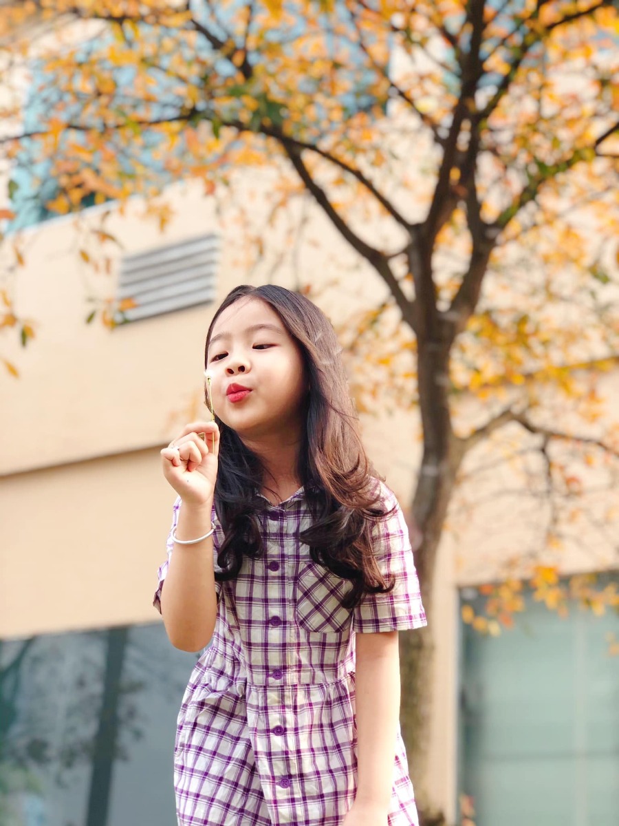 Chào các cô chú, lại là em bé đây ạ. Bữa nay em bé lên công ty mẹ chơi, gặp cây lộc vừng yêu quá nên làm ngay bộ ảnh Hàn Quốc giữa lòng thị trấn nhỏ ạ.
Điện thoại mẹ em bé không hịn lắm nên ảnh hơi kém chất lượng ạ.
Xin phép trình bày quy trình chụp ảnh cho mẫu nhí ạ:
Bước 1: Chọn trang phục và phụ kiện hợp tone màu với cảnh (như bộ này là mẫu mặc sẵn vậy lên công ty mẹ cháu nên cũng không có chuẩn bị trước, nhưng mẹ cháu nhanh mắt nhanh tay kiếm ngay quyển sách tim tím hoa sim mang ra cho đồng bộ).
Bước 2: Ngon ngọt dùng lời động viên, tạo tâm lý thoải mái cho mẫu (có thể tỏ ra đau khổ khi mẫu không hợp tác, tuyệt đối không doạ dẫm). Trêu mẫu, nói chuyện với mẫu tưng bừng lên để bắt khoảnh khắc tự nhiên.
Bước 3: Photographer nằm ngửa ra (dạ, mẹ cháu không nói đùa, chính xác là nằm ngửa ra bãi cỏ chụp từ dưới lên đó ạ vì cái tán cây nó cao lắm).
Bước 4: Mở điện thoại chế độ chân dung, căn cho máy nhận diện và khoá chủ thể (có chữ “ánh sáng tự nhiên “ màu vàng hiện ra là ok) rồi chụp lấy chụp để.
Bước 5: Tải app Meitu, vào phần chỉnh sửa kéo độ sáng, màu sắc lên một xíu, vào filter chọn màu theo tổ tiên mách bảo, không có công thức cố định nào cả, vừa mắt là được thôi. Lưu ý là có thể chồng 1,2,3 filter cho đạt màu ưng ý, có thể crop bớt hoặc xoay cho ảnh cân đối, sau đó vào chỉnh sửa kéo phần “chi tiết” lên (để tăng độ nét).