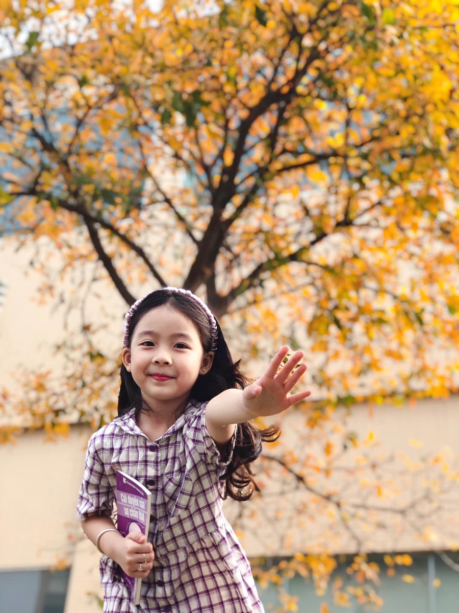 Chào các cô chú, lại là em bé đây ạ. Bữa nay em bé lên công ty mẹ chơi, gặp cây lộc vừng yêu quá nên làm ngay bộ ảnh Hàn Quốc giữa lòng thị trấn nhỏ ạ.
Điện thoại mẹ em bé không hịn lắm nên ảnh hơi kém chất lượng ạ.
Xin phép trình bày quy trình chụp ảnh cho mẫu nhí ạ:
Bước 1: Chọn trang phục và phụ kiện hợp tone màu với cảnh (như bộ này là mẫu mặc sẵn vậy lên công ty mẹ cháu nên cũng không có chuẩn bị trước, nhưng mẹ cháu nhanh mắt nhanh tay kiếm ngay quyển sách tim tím hoa sim mang ra cho đồng bộ).
Bước 2: Ngon ngọt dùng lời động viên, tạo tâm lý thoải mái cho mẫu (có thể tỏ ra đau khổ khi mẫu không hợp tác, tuyệt đối không doạ dẫm). Trêu mẫu, nói chuyện với mẫu tưng bừng lên để bắt khoảnh khắc tự nhiên.
Bước 3: Photographer nằm ngửa ra (dạ, mẹ cháu không nói đùa, chính xác là nằm ngửa ra bãi cỏ chụp từ dưới lên đó ạ vì cái tán cây nó cao lắm).
Bước 4: Mở điện thoại chế độ chân dung, căn cho máy nhận diện và khoá chủ thể (có chữ “ánh sáng tự nhiên “ màu vàng hiện ra là ok) rồi chụp lấy chụp để.
Bước 5: Tải app Meitu, vào phần chỉnh sửa kéo độ sáng, màu sắc lên một xíu, vào filter chọn màu theo tổ tiên mách bảo, không có công thức cố định nào cả, vừa mắt là được thôi. Lưu ý là có thể chồng 1,2,3 filter cho đạt màu ưng ý, có thể crop bớt hoặc xoay cho ảnh cân đối, sau đó vào chỉnh sửa kéo phần “chi tiết” lên (để tăng độ nét).