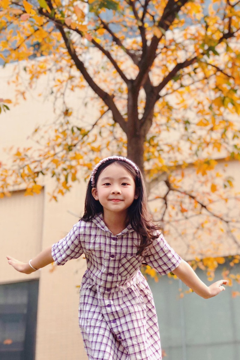 Chào các cô chú, lại là em bé đây ạ. Bữa nay em bé lên công ty mẹ chơi, gặp cây lộc vừng yêu quá nên làm ngay bộ ảnh Hàn Quốc giữa lòng thị trấn nhỏ ạ.
Điện thoại mẹ em bé không hịn lắm nên ảnh hơi kém chất lượng ạ.
Xin phép trình bày quy trình chụp ảnh cho mẫu nhí ạ:
Bước 1: Chọn trang phục và phụ kiện hợp tone màu với cảnh (như bộ này là mẫu mặc sẵn vậy lên công ty mẹ cháu nên cũng không có chuẩn bị trước, nhưng mẹ cháu nhanh mắt nhanh tay kiếm ngay quyển sách tim tím hoa sim mang ra cho đồng bộ).
Bước 2: Ngon ngọt dùng lời động viên, tạo tâm lý thoải mái cho mẫu (có thể tỏ ra đau khổ khi mẫu không hợp tác, tuyệt đối không doạ dẫm). Trêu mẫu, nói chuyện với mẫu tưng bừng lên để bắt khoảnh khắc tự nhiên.
Bước 3: Photographer nằm ngửa ra (dạ, mẹ cháu không nói đùa, chính xác là nằm ngửa ra bãi cỏ chụp từ dưới lên đó ạ vì cái tán cây nó cao lắm).
Bước 4: Mở điện thoại chế độ chân dung, căn cho máy nhận diện và khoá chủ thể (có chữ “ánh sáng tự nhiên “ màu vàng hiện ra là ok) rồi chụp lấy chụp để.
Bước 5: Tải app Meitu, vào phần chỉnh sửa kéo độ sáng, màu sắc lên một xíu, vào filter chọn màu theo tổ tiên mách bảo, không có công thức cố định nào cả, vừa mắt là được thôi. Lưu ý là có thể chồng 1,2,3 filter cho đạt màu ưng ý, có thể crop bớt hoặc xoay cho ảnh cân đối, sau đó vào chỉnh sửa kéo phần “chi tiết” lên (để tăng độ nét).