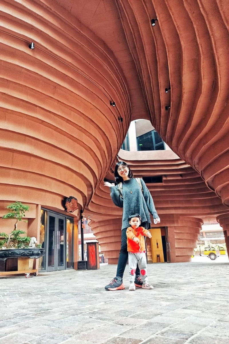 RÌ VIU NHANH BẢO TÀNG GỐM BÁT TRÀNG 🏺

Còn nhớ lần gần nhất mình đến Bát Tràng là lúc bụng bầu hơn 8 tháng, đi cùng em gái, trên chuyến xe buýt. Và đó cũng là chuyến đi cuối cùng trước khi mình lên bàn đẻ. Ấp ủ quay lại đây cùng con mà mãi đến tận giờ mới đi được, điểm đến mình lựa chọn là bảo tàng gốm Bát Tràng mới xây năm ngoái. Cùng mình rì viu nhanh xem chỗ này có gì chơi nhé!

Tụi mình chọn đi xe máy cho chủ động, đường đi google map là ra, đến nơi thì gửi xe ở bãi ngay bên cạnh (10k/xe). Sau đó vào cổng mua vé. Nhà mình có 2 người lớn, 1 bé 2 tuổi rưỡi nên mua 2 vé tham quan (30k/người), 2 vé hương sa trà (40k/người), 1 vé trải nghiệm Tôi làm nghệ nhân (50k/người). Mình không mua vé xe điện (30k/người còn thuê cả xe là 250k/xe) vì mỗi chuyến chỉ có thời gian 30 phút và không được chuyển xe nên không tham quan được mấy.

#1 Quảng trường gốm (tầng 1)

Đây là nơi nhìn rõ nhất kiến trúc độc đáo của bảo tàng. Rất nhiều hình xoắn ốc màu đất nung khổng lồ. Thiết kế các vòng xoắn to dần lên trên siêu thông minh, bề ngoài thì trông như bàn vuốt gốm, còn bên trong lại chính là các bục bày gốm và cầu thang để đi.

Tuy nhiên mình không thấy trưng bày các sản phẩm mỹ nghệ ngoài sân như các bài trên mạng, có thể chỉ khi có sự kiện lớn người ta mới bày ra. Dưới này còn có các khu trưng bày giới thiệu sản phẩm gốm nổi tiếng Bát Tràng nhưng cũng chỗ đóng chỗ mở.

#2 Trải nghiệm nặn gốm (tầng G)

Không gian ở đây rất mát mẻ, rộng rãi, nhiều ánh sáng. Mình được phát 1 yếm đeo, 1 tảng đất sét, ngồi ở bàn xoay, có người hướng dẫn nặn. Nặn xong ra ngoài để khò cho cứng xong tô màu và mang về. Bên cạnh có cả khu tô tượng. Bé nhà mình lần đầu được chạm tay vào đất sét thích thú kêu "Lạnh quá", hết sờ mó xoè tay xoay xoay lại thò tay xuống xô nước bên cạnh rửa, kết quả là tảng đất sét càng ngày càng ướt, không nặn được ra hình gì cả 😂

Thích cái là ở đây bạn muốn nặn bao lâu tùy thích. Mình nhớ hồi xưa đi nặn ở nhà dân không dược thoải mái như thế, còn bị cô chủ giục làm nhanh còn đóng cửa, xong sốt ruột ngồi làm hộ mang đi nung luôn cho nhanh, mà cũng 50k/người.

#3 Thưởng trà và các tác phẩm điêu khắc ánh sáng (tầng 5)

Vé ghi là thưởng trà ủ mát nhưng trên thực tế bạn sẽ chỉ được uống trà ô long ủ mát miễn phí thôi, còn các trà khác nếu muốn thử phải mua. Trà khá thơm, tuy nhiên hơi nhạt. Còn các tác phẩm điêu khắc ánh sáng số lượng hơi ít, có người giới thiệu tuy nhiên ngắn có vài phút thôi. Xung quanh trang trí không đặc sắc lắm, kiểu vườn hoa cây cảnh, view xuống thành phố. Nói chung không nhiều hoạt động hay ho tương xứng với giá vé lắm.

Điểm gỡ duy nhất ở đây là có bàn uống trà làm từ thân cây thành bể cá rất độc đáo. Bạn nhà tớ mê cái bàn này lắm vì có bao nhiêu là cá bảy màu bơi tung tăng. Ngoài ra chỗ này cũng phù hợp cho bạn nào muốn chụp ảnh cổ vì ở đây có cho thuê trang phục với giá 80k/bộ.

#4 Còn khu trưng bày giới thiệu giúp mọi người tìm hiểu về sự hình thành phát triển của làng nghề nổi tiếng của Việt Nam ở tầng 2,3 nữa nhưng đang trong giai đoạn sửa chữa. Nói chung cũng không tương xứng với giá vé tham quan 30k/người lắm.

Túm lại, đi một lần cho biết thôi, điểm sáng duy nhất ở đây là khu vực nặn gốm, còn lại bảo tàng nên bổ sung nhiều hoạt động hơn, hoặc giá vé tham quan bao gồm cả hương sa quán vì khu trưng bày bị đóng cửa mất rồi 😅