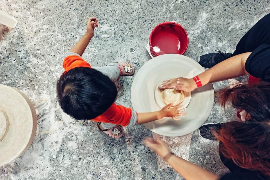 RÌ VIU NHANH BẢO TÀNG GỐM BÁT TRÀNG 🏺

Còn nhớ lần gần nhất mình đến Bát Tràng là lúc bụng bầu hơn 8 tháng, đi cùng em gái, trên chuyến xe buýt. Và đó cũng là chuyến đi cuối cùng trước khi mình lên bàn đẻ. Ấp ủ quay lại đây cùng con mà mãi đến tận giờ mới đi được, điểm đến mình lựa chọn là bảo tàng gốm Bát Tràng mới xây năm ngoái. Cùng mình rì viu nhanh xem chỗ này có gì chơi nhé!

Tụi mình chọn đi xe máy cho chủ động, đường đi google map là ra, đến nơi thì gửi xe ở bãi ngay bên cạnh (10k/xe). Sau đó vào cổng mua vé. Nhà mình có 2 người lớn, 1 bé 2 tuổi rưỡi nên mua 2 vé tham quan (30k/người), 2 vé hương sa trà (40k/người), 1 vé trải nghiệm Tôi làm nghệ nhân (50k/người). Mình không mua vé xe điện (30k/người còn thuê cả xe là 250k/xe) vì mỗi chuyến chỉ có thời gian 30 phút và không được chuyển xe nên không tham quan được mấy.

#1 Quảng trường gốm (tầng 1)

Đây là nơi nhìn rõ nhất kiến trúc độc đáo của bảo tàng. Rất nhiều hình xoắn ốc màu đất nung khổng lồ. Thiết kế các vòng xoắn to dần lên trên siêu thông minh, bề ngoài thì trông như bàn vuốt gốm, còn bên trong lại chính là các bục bày gốm và cầu thang để đi.

Tuy nhiên mình không thấy trưng bày các sản phẩm mỹ nghệ ngoài sân như các bài trên mạng, có thể chỉ khi có sự kiện lớn người ta mới bày ra. Dưới này còn có các khu trưng bày giới thiệu sản phẩm gốm nổi tiếng Bát Tràng nhưng cũng chỗ đóng chỗ mở.

#2 Trải nghiệm nặn gốm (tầng G)

Không gian ở đây rất mát mẻ, rộng rãi, nhiều ánh sáng. Mình được phát 1 yếm đeo, 1 tảng đất sét, ngồi ở bàn xoay, có người hướng dẫn nặn. Nặn xong ra ngoài để khò cho cứng xong tô màu và mang về. Bên cạnh có cả khu tô tượng. Bé nhà mình lần đầu được chạm tay vào đất sét thích thú kêu "Lạnh quá", hết sờ mó xoè tay xoay xoay lại thò tay xuống xô nước bên cạnh rửa, kết quả là tảng đất sét càng ngày càng ướt, không nặn được ra hình gì cả 😂

Thích cái là ở đây bạn muốn nặn bao lâu tùy thích. Mình nhớ hồi xưa đi nặn ở nhà dân không dược thoải mái như thế, còn bị cô chủ giục làm nhanh còn đóng cửa, xong sốt ruột ngồi làm hộ mang đi nung luôn cho nhanh, mà cũng 50k/người.

#3 Thưởng trà và các tác phẩm điêu khắc ánh sáng (tầng 5)

Vé ghi là thưởng trà ủ mát nhưng trên thực tế bạn sẽ chỉ được uống trà ô long ủ mát miễn phí thôi, còn các trà khác nếu muốn thử phải mua. Trà khá thơm, tuy nhiên hơi nhạt. Còn các tác phẩm điêu khắc ánh sáng số lượng hơi ít, có người giới thiệu tuy nhiên ngắn có vài phút thôi. Xung quanh trang trí không đặc sắc lắm, kiểu vườn hoa cây cảnh, view xuống thành phố. Nói chung không nhiều hoạt động hay ho tương xứng với giá vé lắm.

Điểm gỡ duy nhất ở đây là có bàn uống trà làm từ thân cây thành bể cá rất độc đáo. Bạn nhà tớ mê cái bàn này lắm vì có bao nhiêu là cá bảy màu bơi tung tăng. Ngoài ra chỗ này cũng phù hợp cho bạn nào muốn chụp ảnh cổ vì ở đây có cho thuê trang phục với giá 80k/bộ.

#4 Còn khu trưng bày giới thiệu giúp mọi người tìm hiểu về sự hình thành phát triển của làng nghề nổi tiếng của Việt Nam ở tầng 2,3 nữa nhưng đang trong giai đoạn sửa chữa. Nói chung cũng không tương xứng với giá vé tham quan 30k/người lắm.

Túm lại, đi một lần cho biết thôi, điểm sáng duy nhất ở đây là khu vực nặn gốm, còn lại bảo tàng nên bổ sung nhiều hoạt động hơn, hoặc giá vé tham quan bao gồm cả hương sa quán vì khu trưng bày bị đóng cửa mất rồi 😅