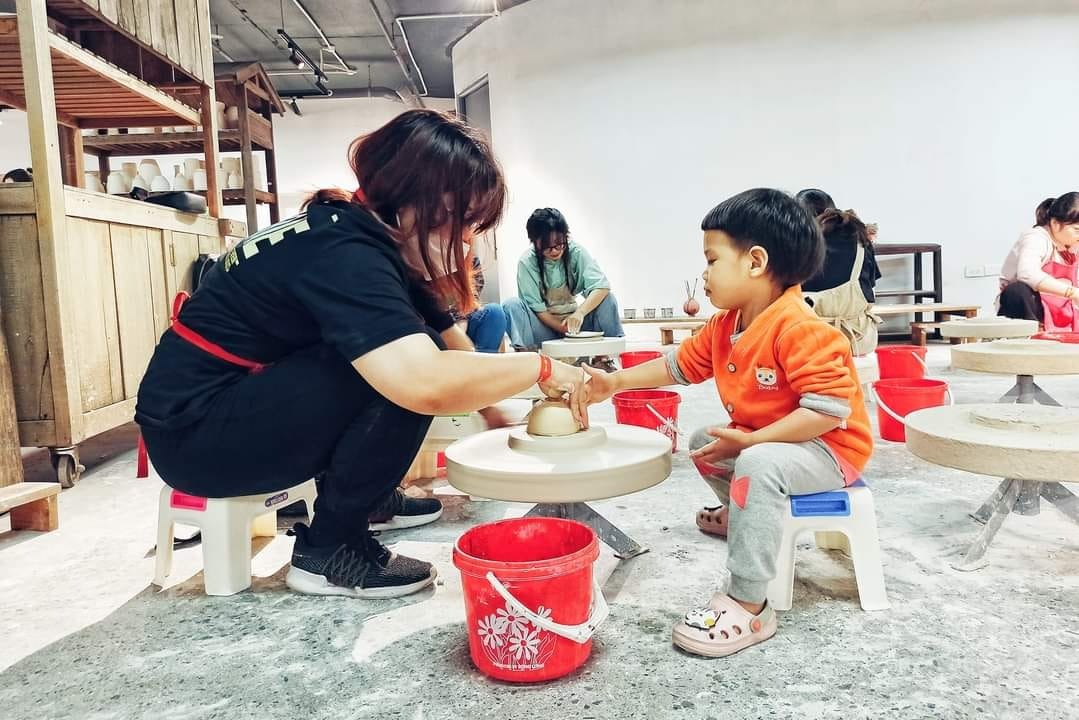 RÌ VIU NHANH BẢO TÀNG GỐM BÁT TRÀNG 🏺

Còn nhớ lần gần nhất mình đến Bát Tràng là lúc bụng bầu hơn 8 tháng, đi cùng em gái, trên chuyến xe buýt. Và đó cũng là chuyến đi cuối cùng trước khi mình lên bàn đẻ. Ấp ủ quay lại đây cùng con mà mãi đến tận giờ mới đi được, điểm đến mình lựa chọn là bảo tàng gốm Bát Tràng mới xây năm ngoái. Cùng mình rì viu nhanh xem chỗ này có gì chơi nhé!

Tụi mình chọn đi xe máy cho chủ động, đường đi google map là ra, đến nơi thì gửi xe ở bãi ngay bên cạnh (10k/xe). Sau đó vào cổng mua vé. Nhà mình có 2 người lớn, 1 bé 2 tuổi rưỡi nên mua 2 vé tham quan (30k/người), 2 vé hương sa trà (40k/người), 1 vé trải nghiệm Tôi làm nghệ nhân (50k/người). Mình không mua vé xe điện (30k/người còn thuê cả xe là 250k/xe) vì mỗi chuyến chỉ có thời gian 30 phút và không được chuyển xe nên không tham quan được mấy.

#1 Quảng trường gốm (tầng 1)

Đây là nơi nhìn rõ nhất kiến trúc độc đáo của bảo tàng. Rất nhiều hình xoắn ốc màu đất nung khổng lồ. Thiết kế các vòng xoắn to dần lên trên siêu thông minh, bề ngoài thì trông như bàn vuốt gốm, còn bên trong lại chính là các bục bày gốm và cầu thang để đi.

Tuy nhiên mình không thấy trưng bày các sản phẩm mỹ nghệ ngoài sân như các bài trên mạng, có thể chỉ khi có sự kiện lớn người ta mới bày ra. Dưới này còn có các khu trưng bày giới thiệu sản phẩm gốm nổi tiếng Bát Tràng nhưng cũng chỗ đóng chỗ mở.

#2 Trải nghiệm nặn gốm (tầng G)

Không gian ở đây rất mát mẻ, rộng rãi, nhiều ánh sáng. Mình được phát 1 yếm đeo, 1 tảng đất sét, ngồi ở bàn xoay, có người hướng dẫn nặn. Nặn xong ra ngoài để khò cho cứng xong tô màu và mang về. Bên cạnh có cả khu tô tượng. Bé nhà mình lần đầu được chạm tay vào đất sét thích thú kêu "Lạnh quá", hết sờ mó xoè tay xoay xoay lại thò tay xuống xô nước bên cạnh rửa, kết quả là tảng đất sét càng ngày càng ướt, không nặn được ra hình gì cả 😂

Thích cái là ở đây bạn muốn nặn bao lâu tùy thích. Mình nhớ hồi xưa đi nặn ở nhà dân không dược thoải mái như thế, còn bị cô chủ giục làm nhanh còn đóng cửa, xong sốt ruột ngồi làm hộ mang đi nung luôn cho nhanh, mà cũng 50k/người.

#3 Thưởng trà và các tác phẩm điêu khắc ánh sáng (tầng 5)

Vé ghi là thưởng trà ủ mát nhưng trên thực tế bạn sẽ chỉ được uống trà ô long ủ mát miễn phí thôi, còn các trà khác nếu muốn thử phải mua. Trà khá thơm, tuy nhiên hơi nhạt. Còn các tác phẩm điêu khắc ánh sáng số lượng hơi ít, có người giới thiệu tuy nhiên ngắn có vài phút thôi. Xung quanh trang trí không đặc sắc lắm, kiểu vườn hoa cây cảnh, view xuống thành phố. Nói chung không nhiều hoạt động hay ho tương xứng với giá vé lắm.

Điểm gỡ duy nhất ở đây là có bàn uống trà làm từ thân cây thành bể cá rất độc đáo. Bạn nhà tớ mê cái bàn này lắm vì có bao nhiêu là cá bảy màu bơi tung tăng. Ngoài ra chỗ này cũng phù hợp cho bạn nào muốn chụp ảnh cổ vì ở đây có cho thuê trang phục với giá 80k/bộ.

#4 Còn khu trưng bày giới thiệu giúp mọi người tìm hiểu về sự hình thành phát triển của làng nghề nổi tiếng của Việt Nam ở tầng 2,3 nữa nhưng đang trong giai đoạn sửa chữa. Nói chung cũng không tương xứng với giá vé tham quan 30k/người lắm.

Túm lại, đi một lần cho biết thôi, điểm sáng duy nhất ở đây là khu vực nặn gốm, còn lại bảo tàng nên bổ sung nhiều hoạt động hơn, hoặc giá vé tham quan bao gồm cả hương sa quán vì khu trưng bày bị đóng cửa mất rồi 😅